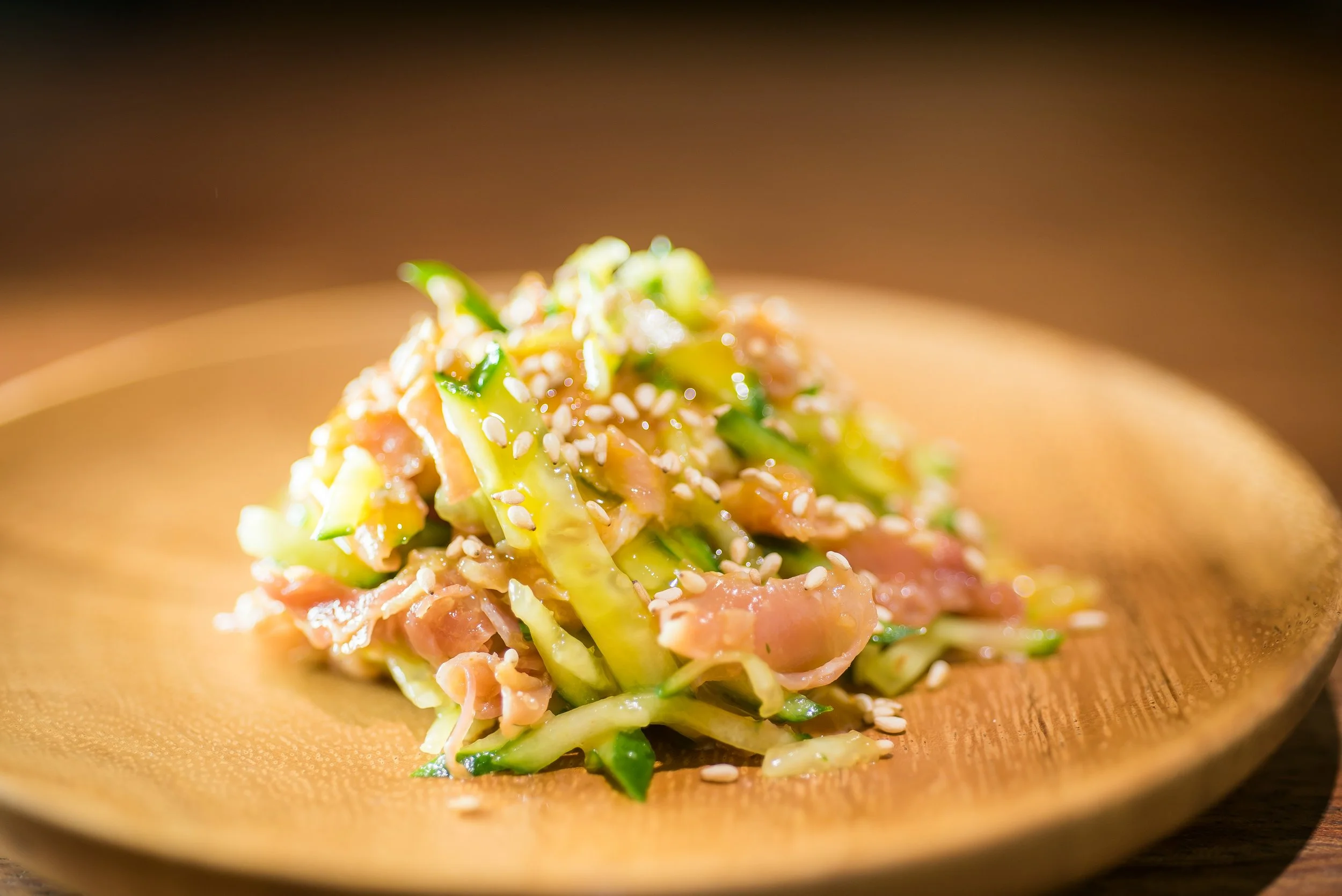 キャベツ、きゅうり、ベーコンの和風サラダに白ごまがかかっている料理