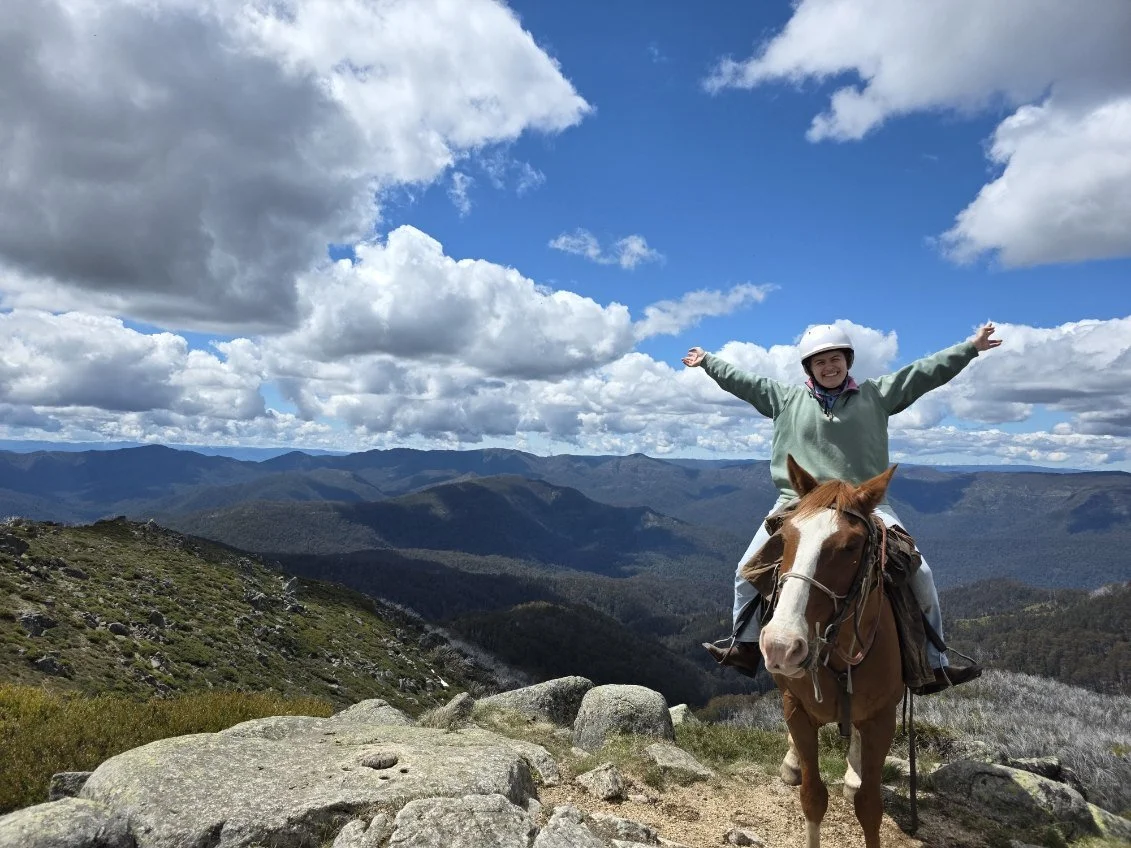 Jojo riding chestnut horse at top of mountain in Australia