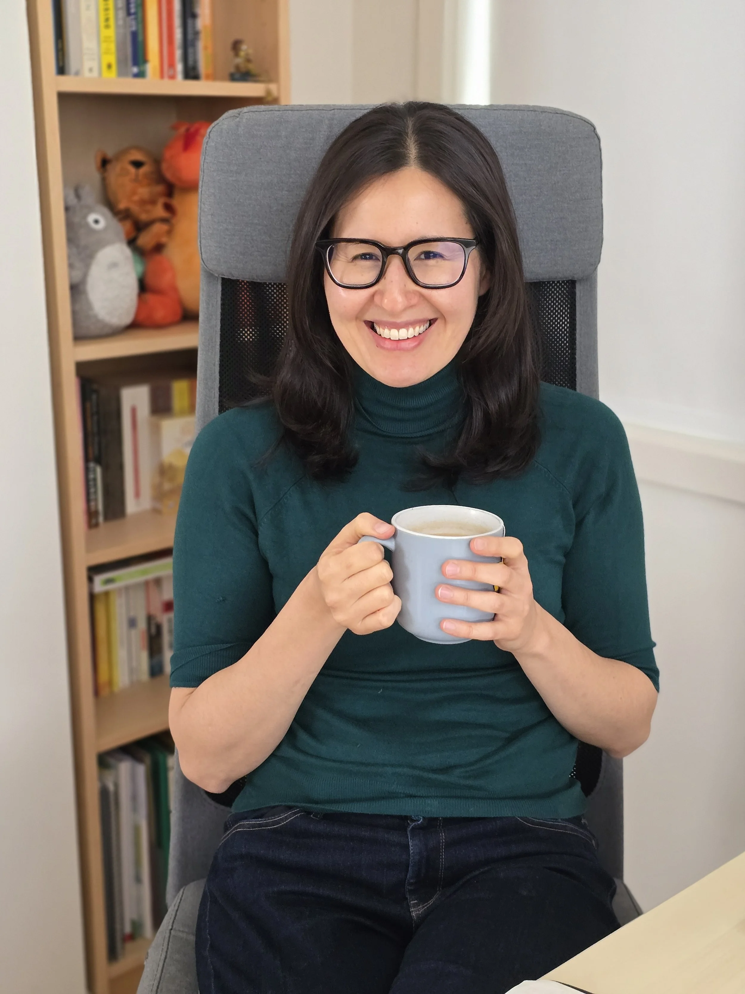 Researcher sitting on a chair at their desk with a cup of tea