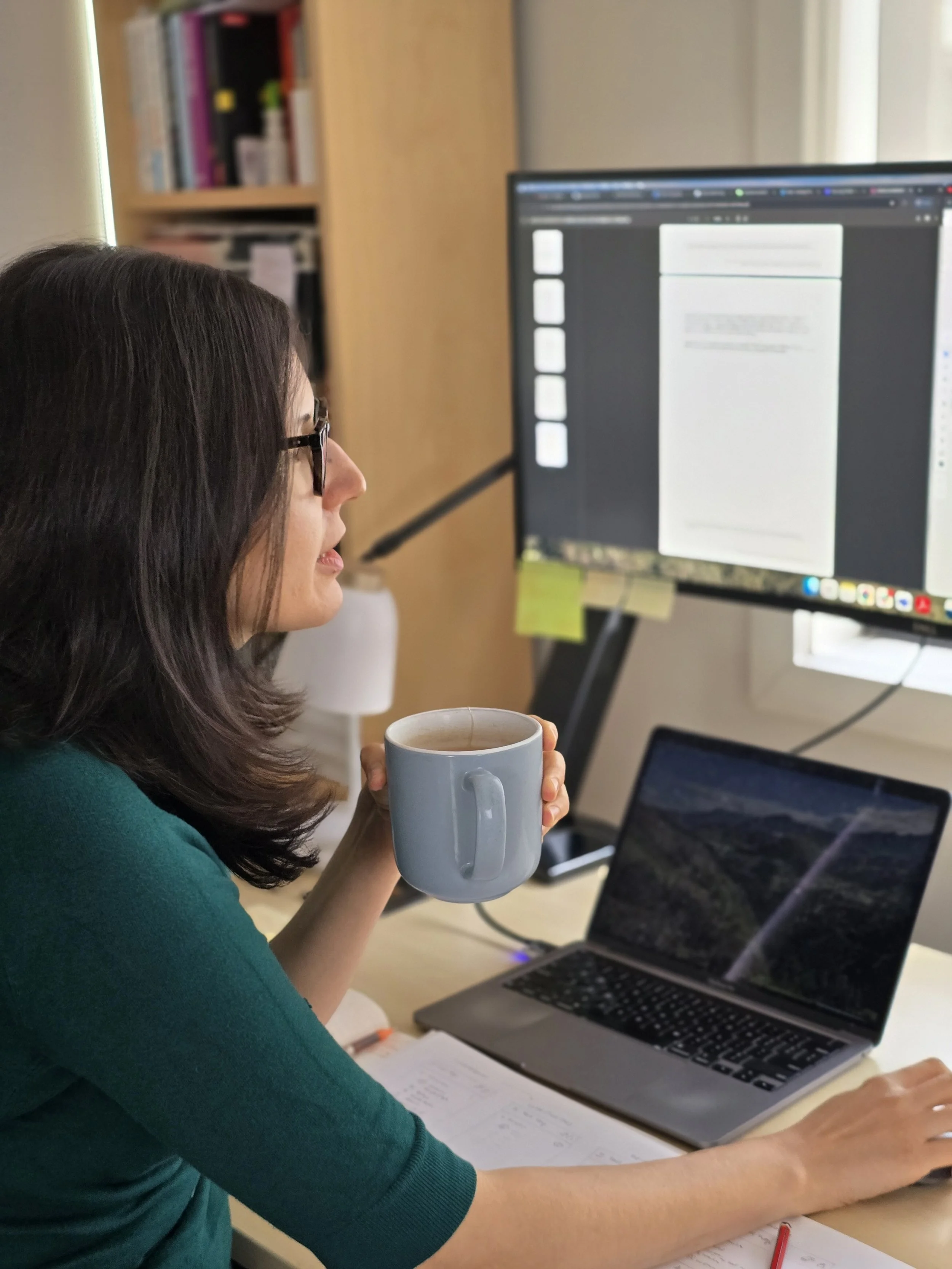Consultant looking at a computer with a mug in their hand