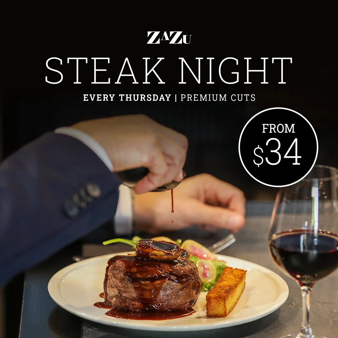 A plate with a cooked steak, green asparagus, mashed potatoes, and two small bowls of green sauce and gravy, with a glass of red wine in the background next to promotional text for a steak night event.