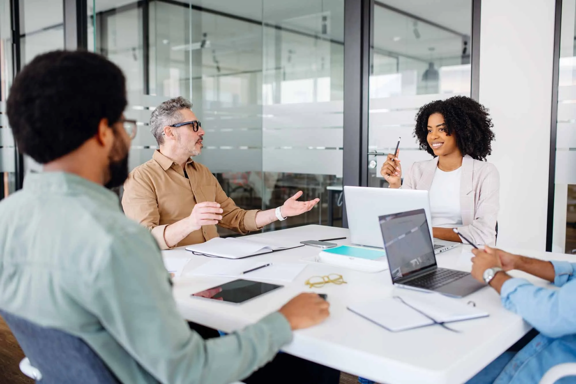 Tre personer runt ett kontorsbord som pratar. Workz rekryterar till olika roller inom kundservice.