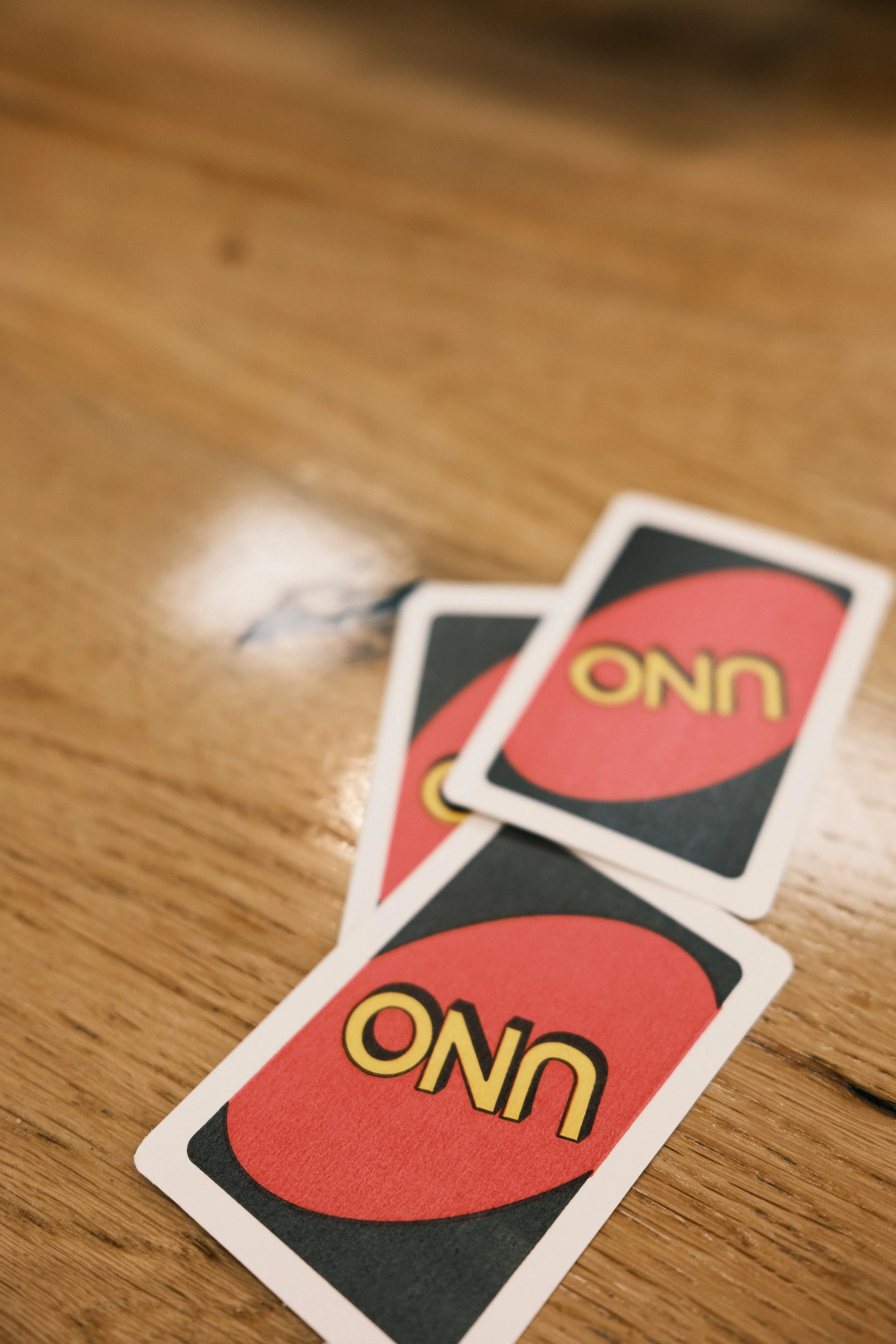 Three UNO game cards with the UNO logo on a wooden surface.