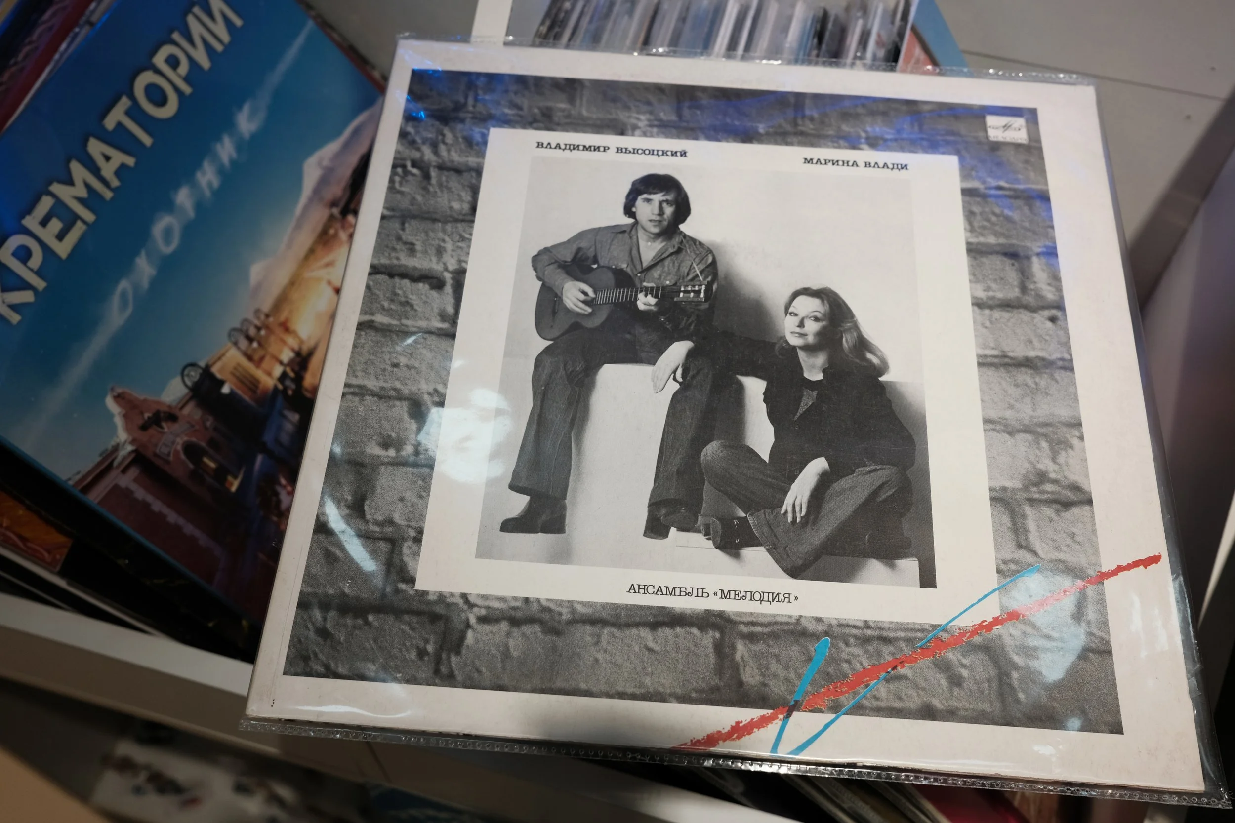 Black and white photograph of a man and woman sitting against a brick wall; the man is playing guitar, and both are looking at the camera. There is Russian text above and below the photo.