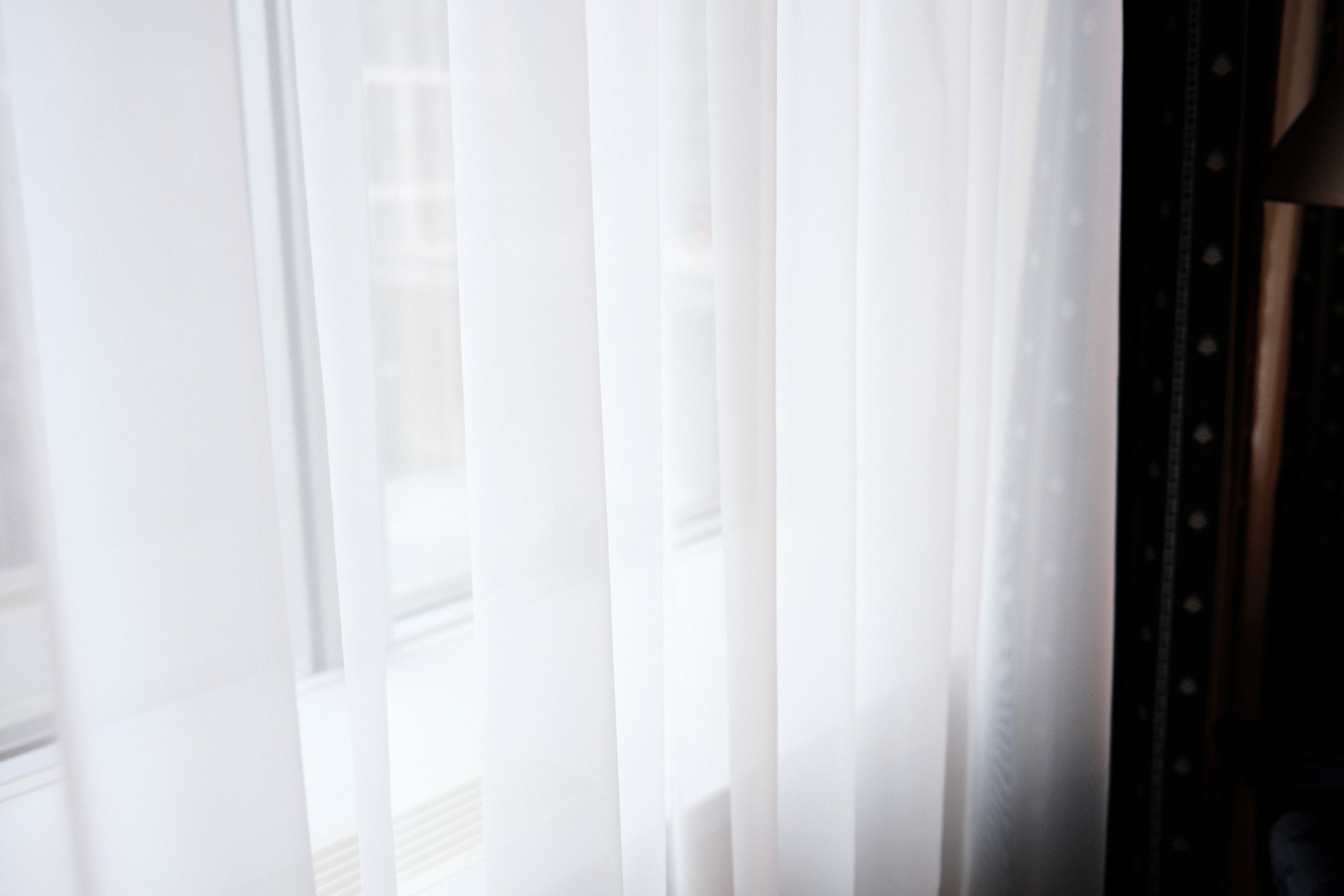 Close-up of window blinds, partly open, with some sunlight filtering through.