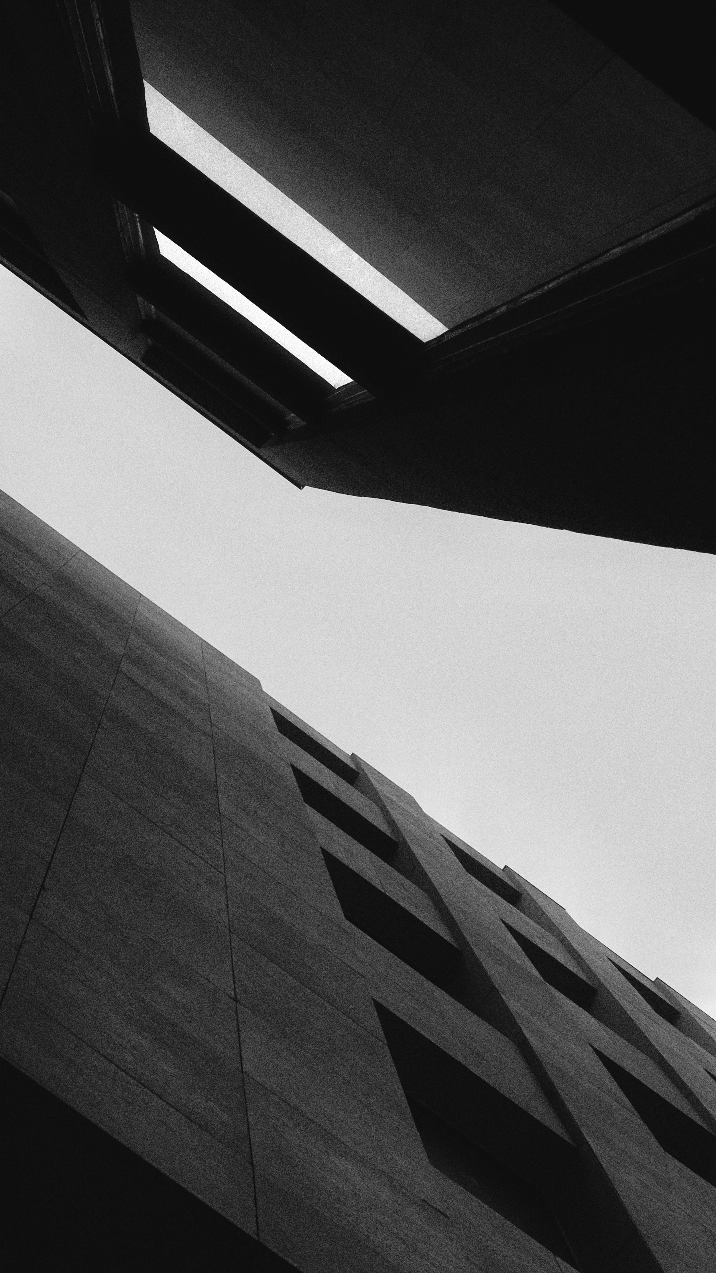 View of a modern building with multiple rectangular windows, taken from a low angle looking upward, in black and white.