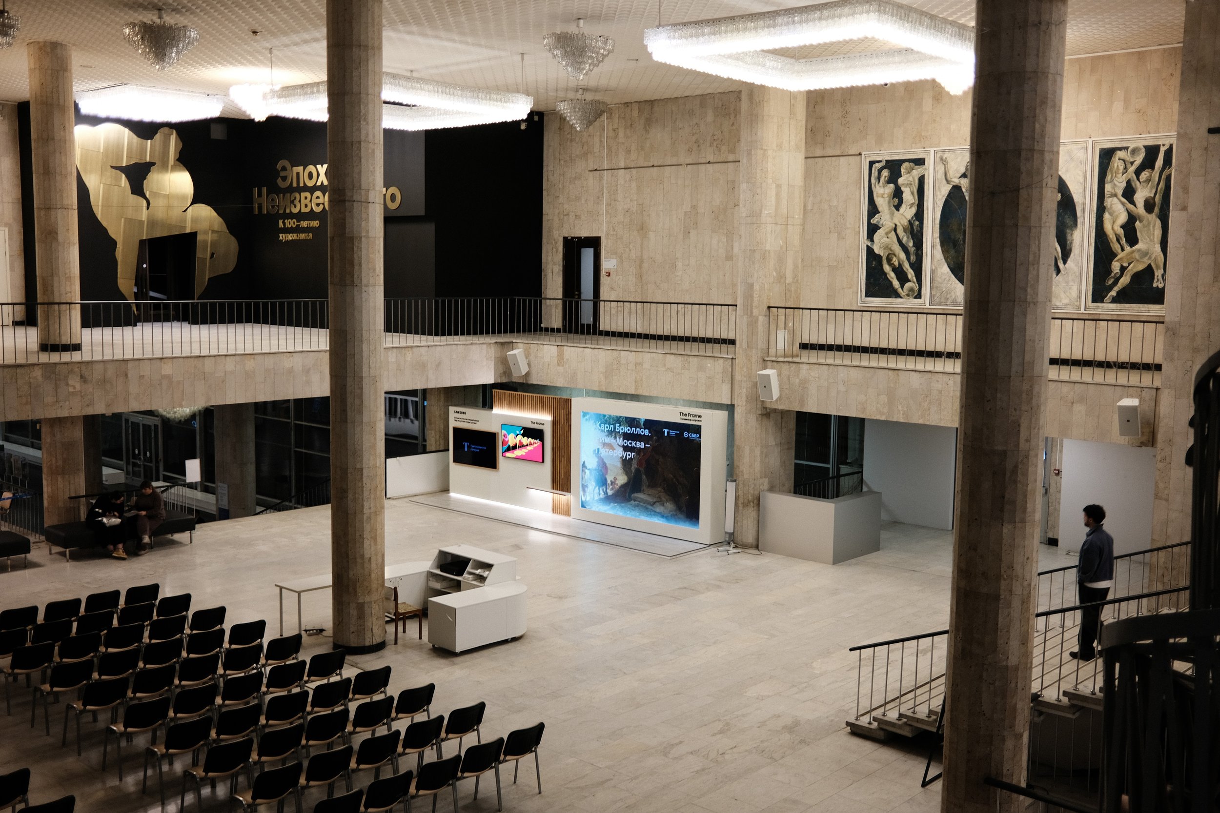Interior of a modern art museum with seating area, digital displays, and artwork on the walls.