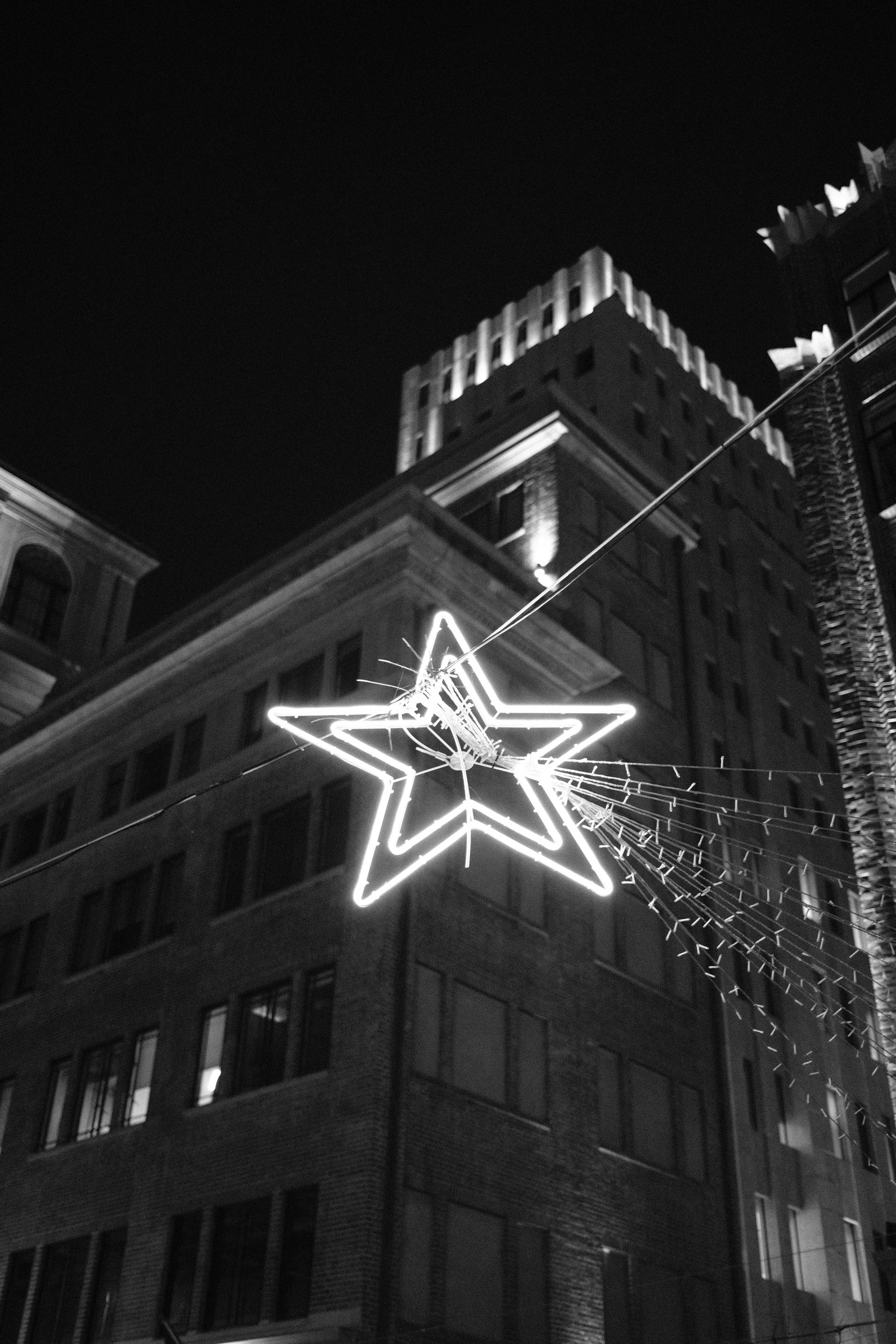 Nighttime city scene with a glowing star-shaped light decoration hanging between buildings.