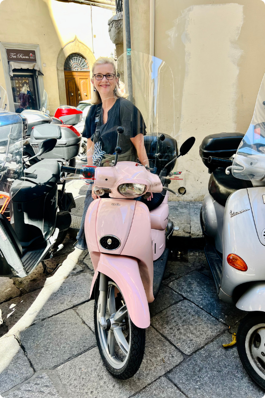 Sarah with a pink Vespa, parked up in Italy