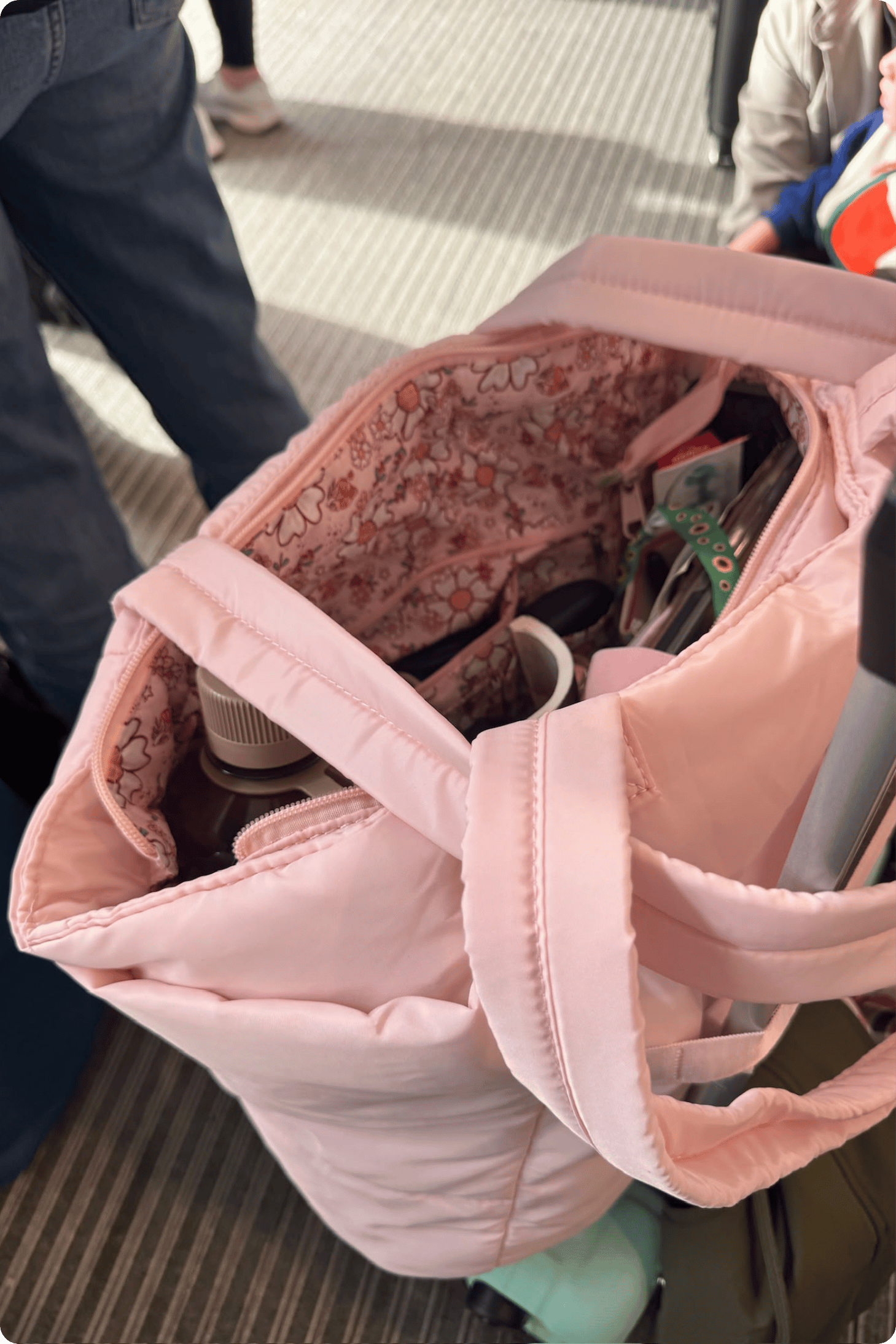 Beara's pink hand luggage page open with a water bottle and sunflower lanyard visible at the top