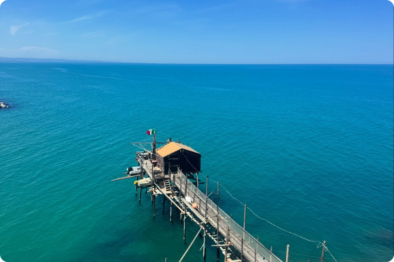 Traditional trabocco fishing platform extending into the turquoise Adriatic Sea on Italy’s Abruzzo coast under a clear blue sky, showcasing one of the region’s most iconic coastal landmarks and scenic hidden gems for slow travel in Italy.