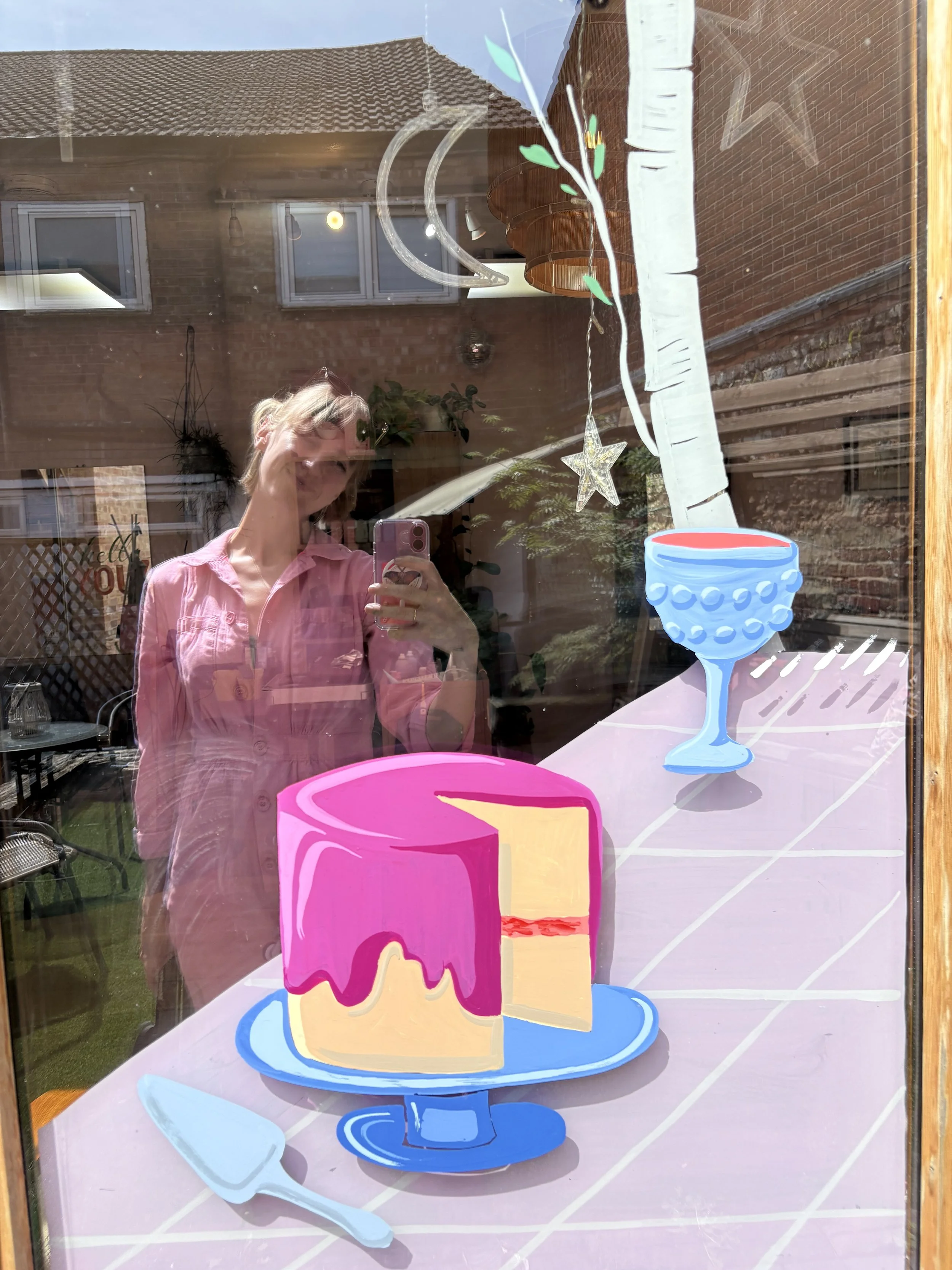 Allie stands in window reflection with a hand painted Picnic scene.