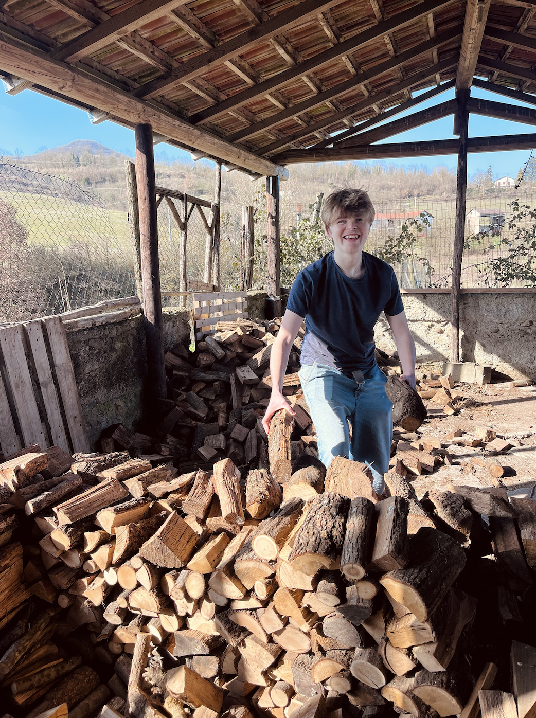 young man piling the wood at intentional community in Italy.png
