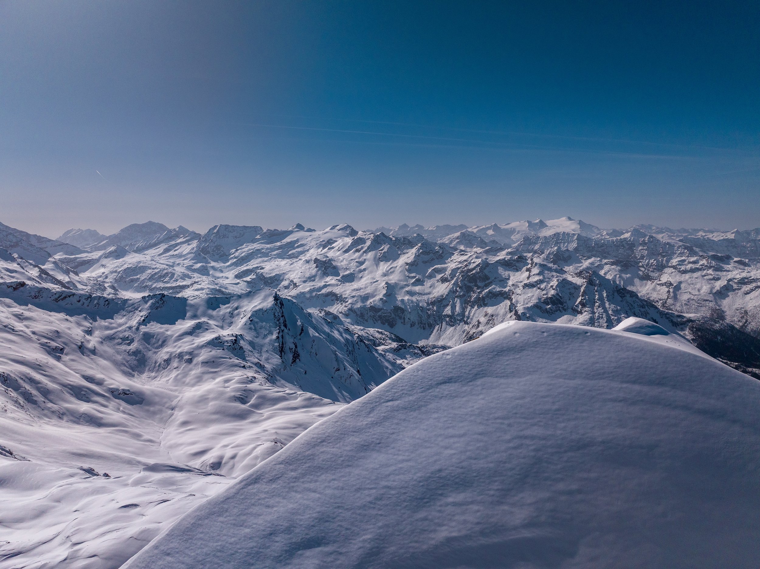 Snow-covered mountain range under a clear blue sky.