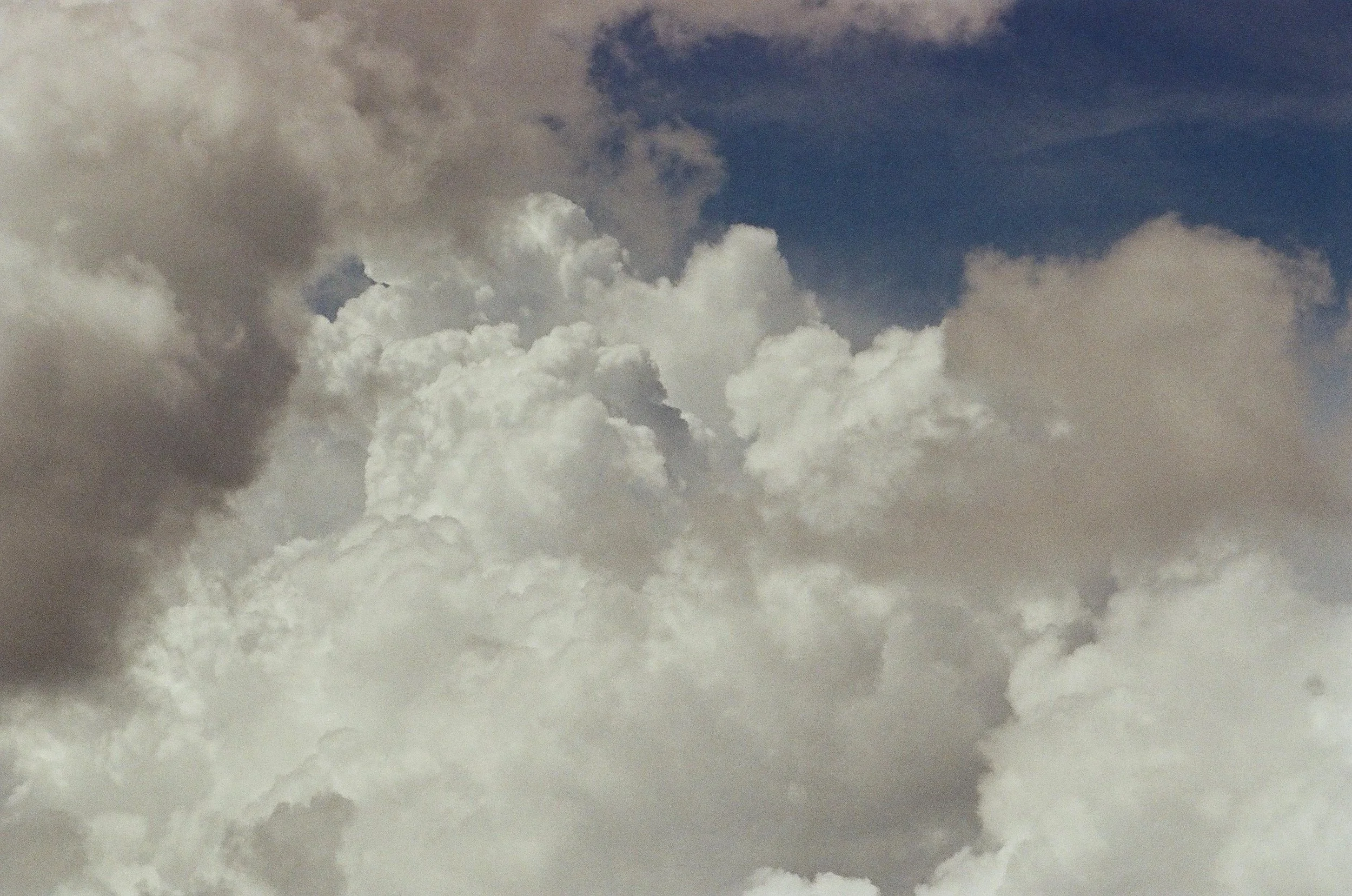 A cloudy sky with a mix of white and dark gray clouds, and patches of blue sky visible.