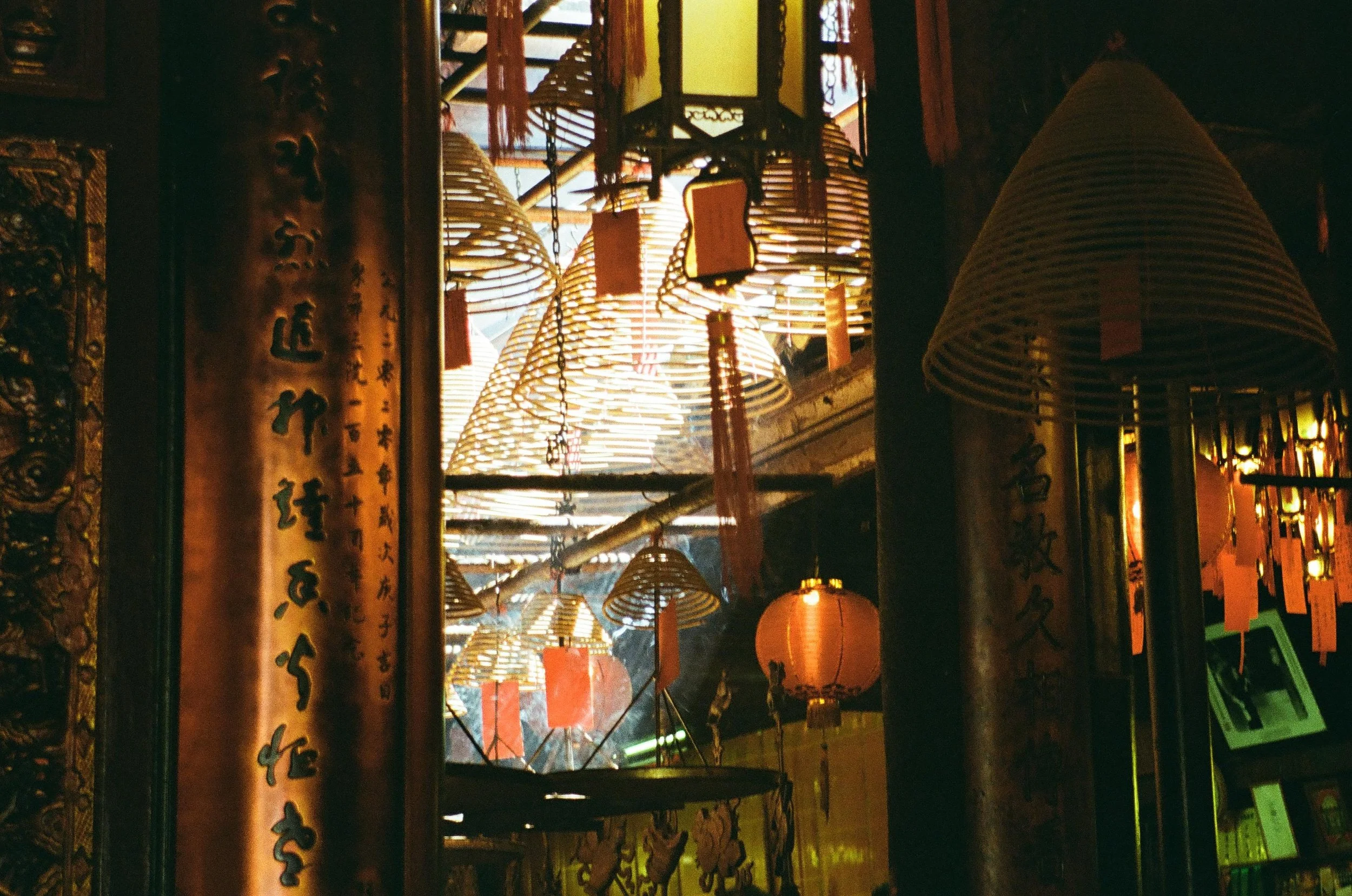 Inside a traditional Asian temple with hanging paper lanterns and bamboo lamps, illuminated by warm, soft lighting.