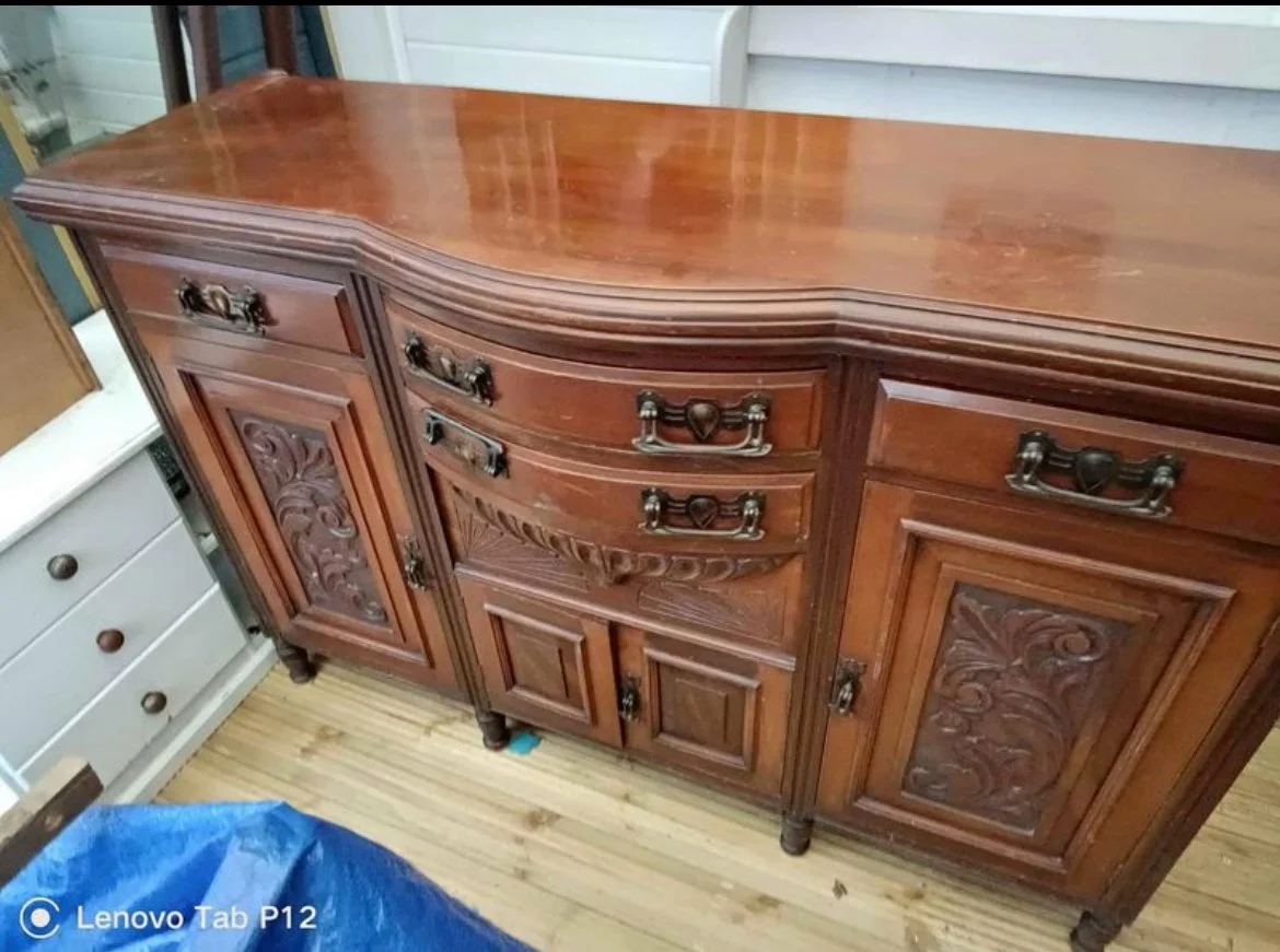 A vintage wooden sideboard with ornate carved details, multiple drawers, and cabinet doors.