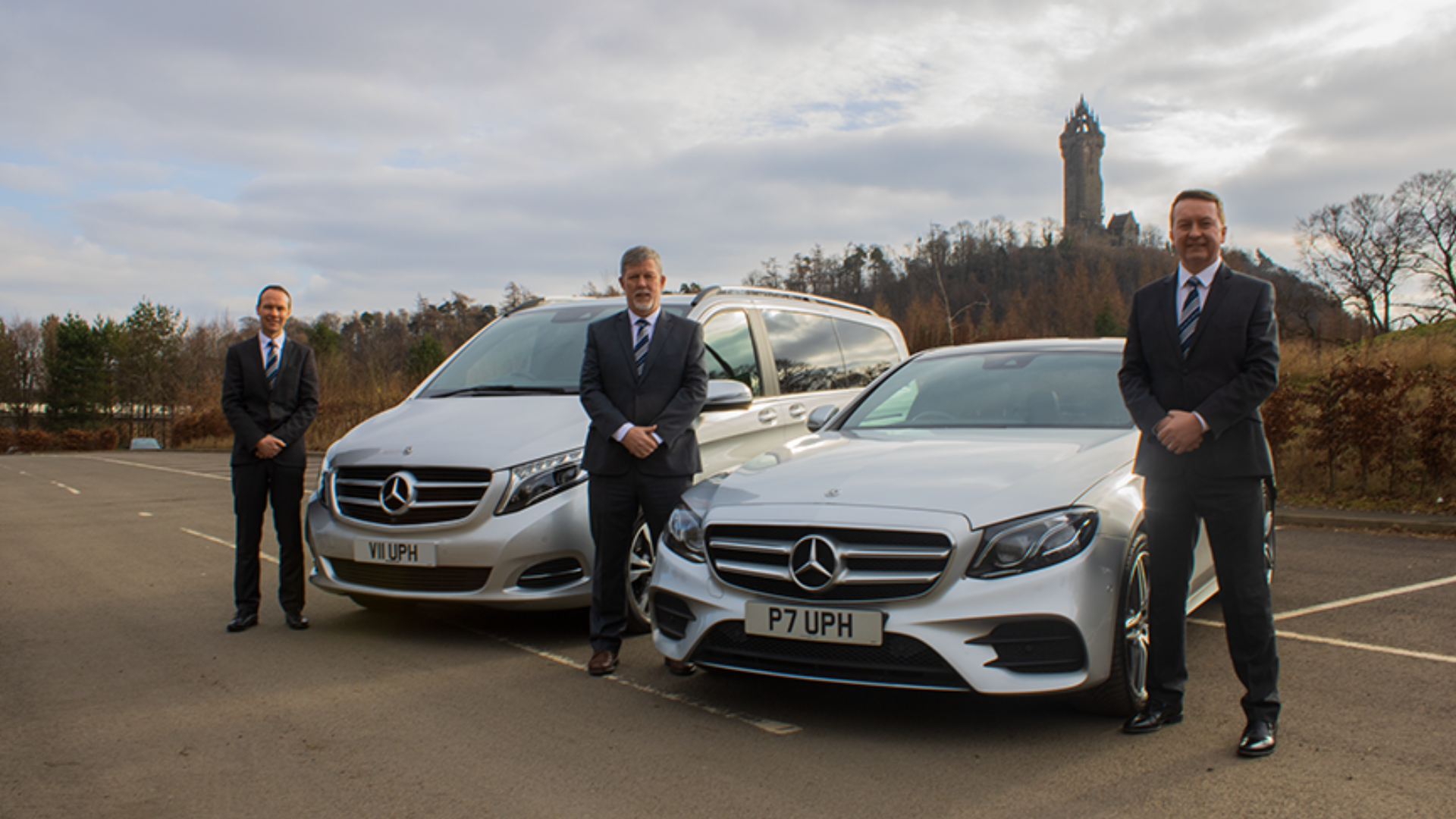 Ultimate Private Hire Team standing next to fleet in front of the Wallace Monument