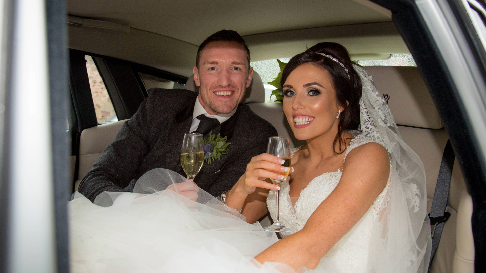 Wedding couple in wedding car drinking champagne
