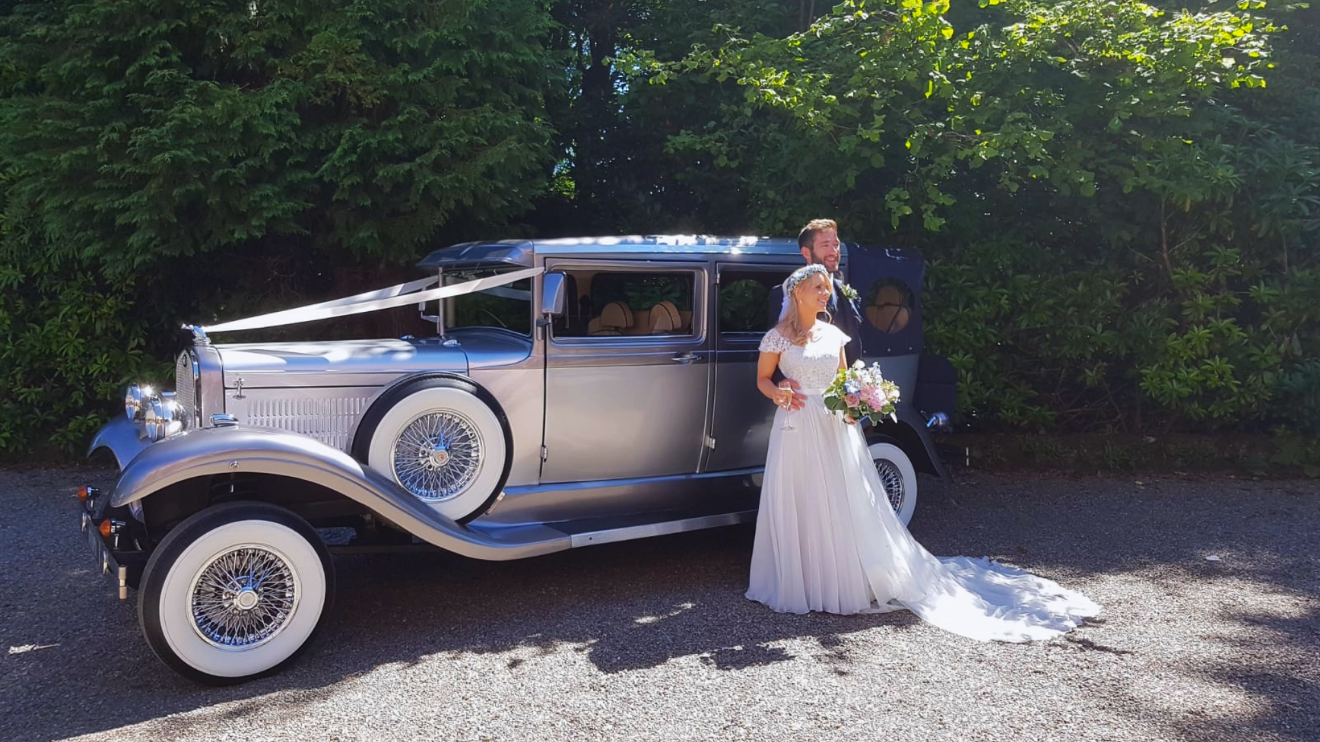 Wedding couple getting photos next to classic branford elite wedding car