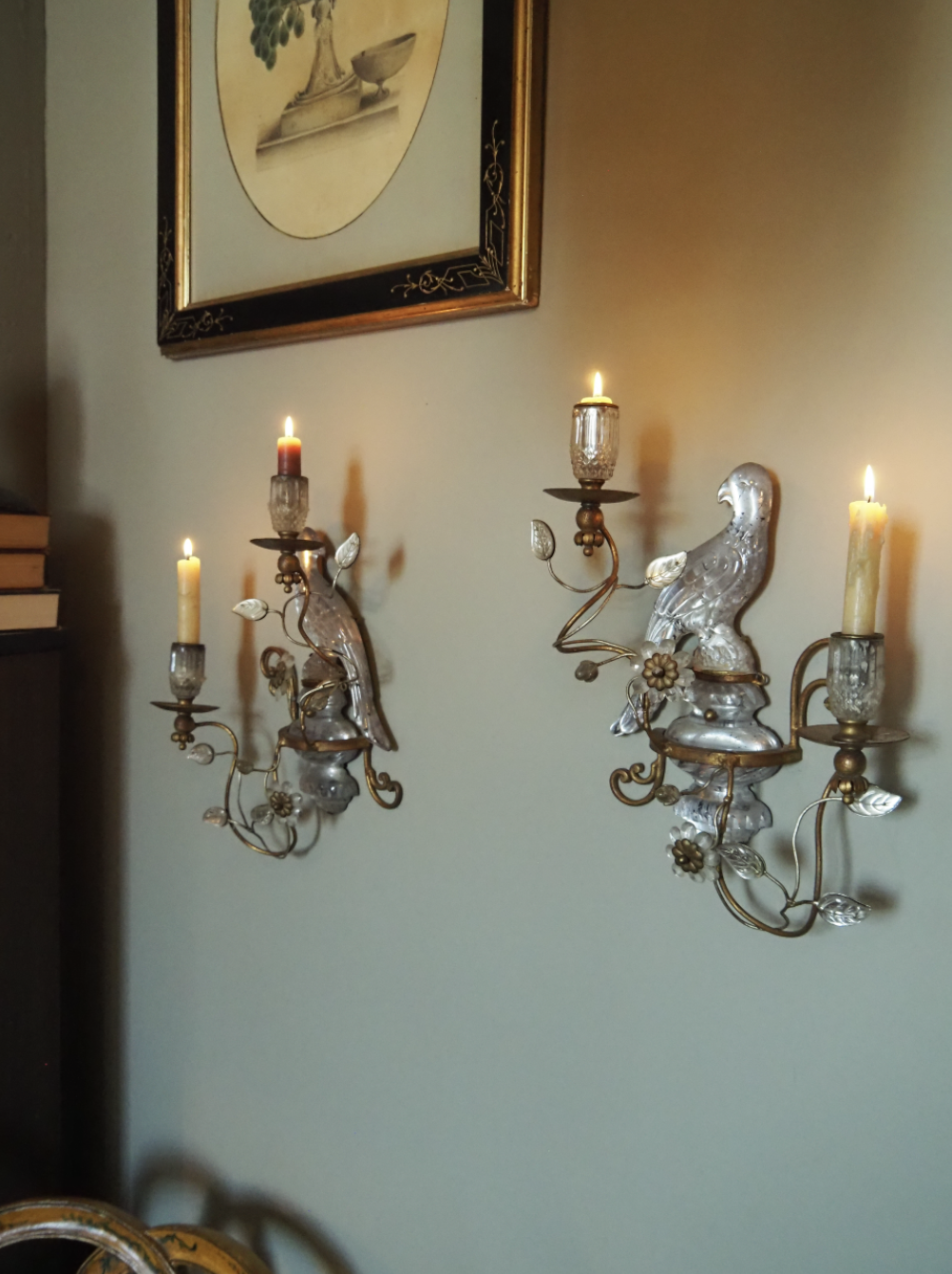 Decorative wall sconces with candle-shaped lights, ornate floral design, and a wall painting above them.