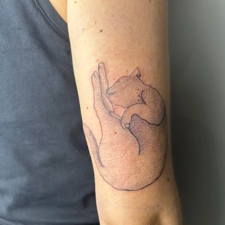 Tattoo eines schlafenden Kätzchens auf dem Arm.