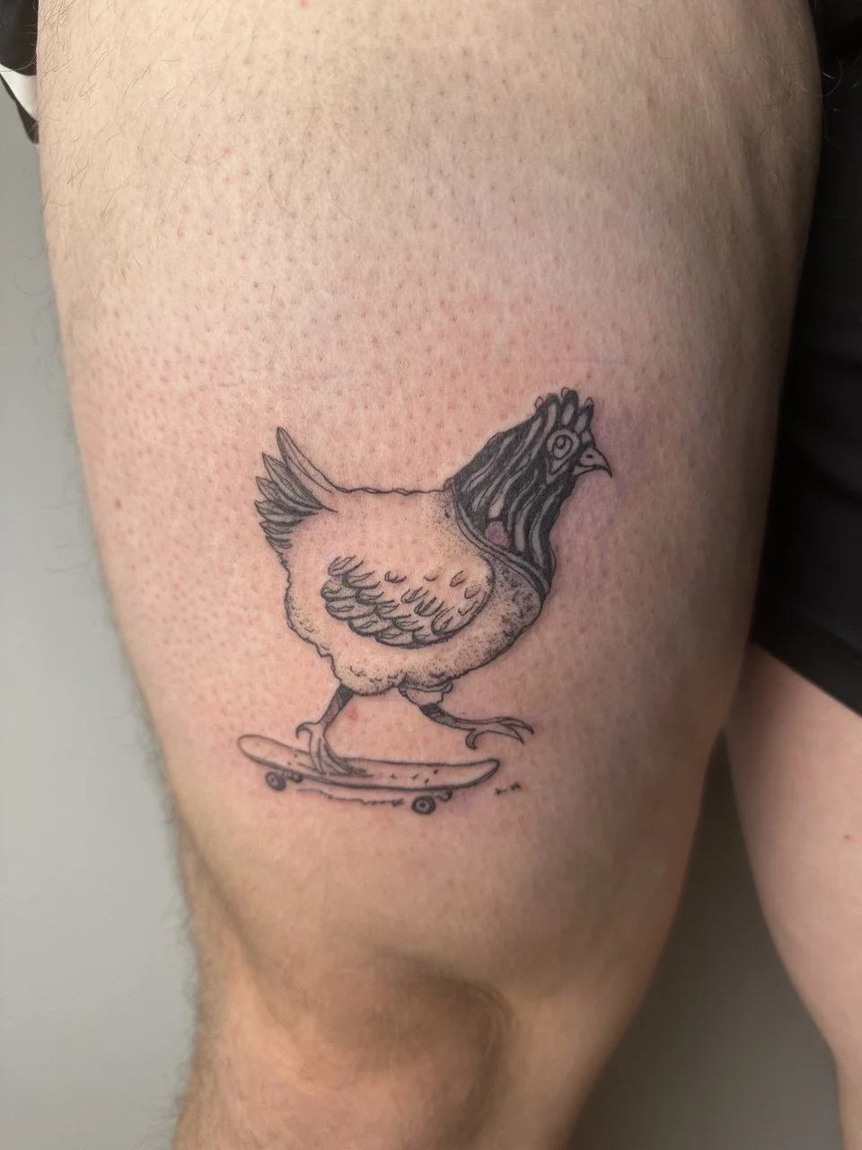 Tattoo eines Huhns, das auf einem Skateboard steht.