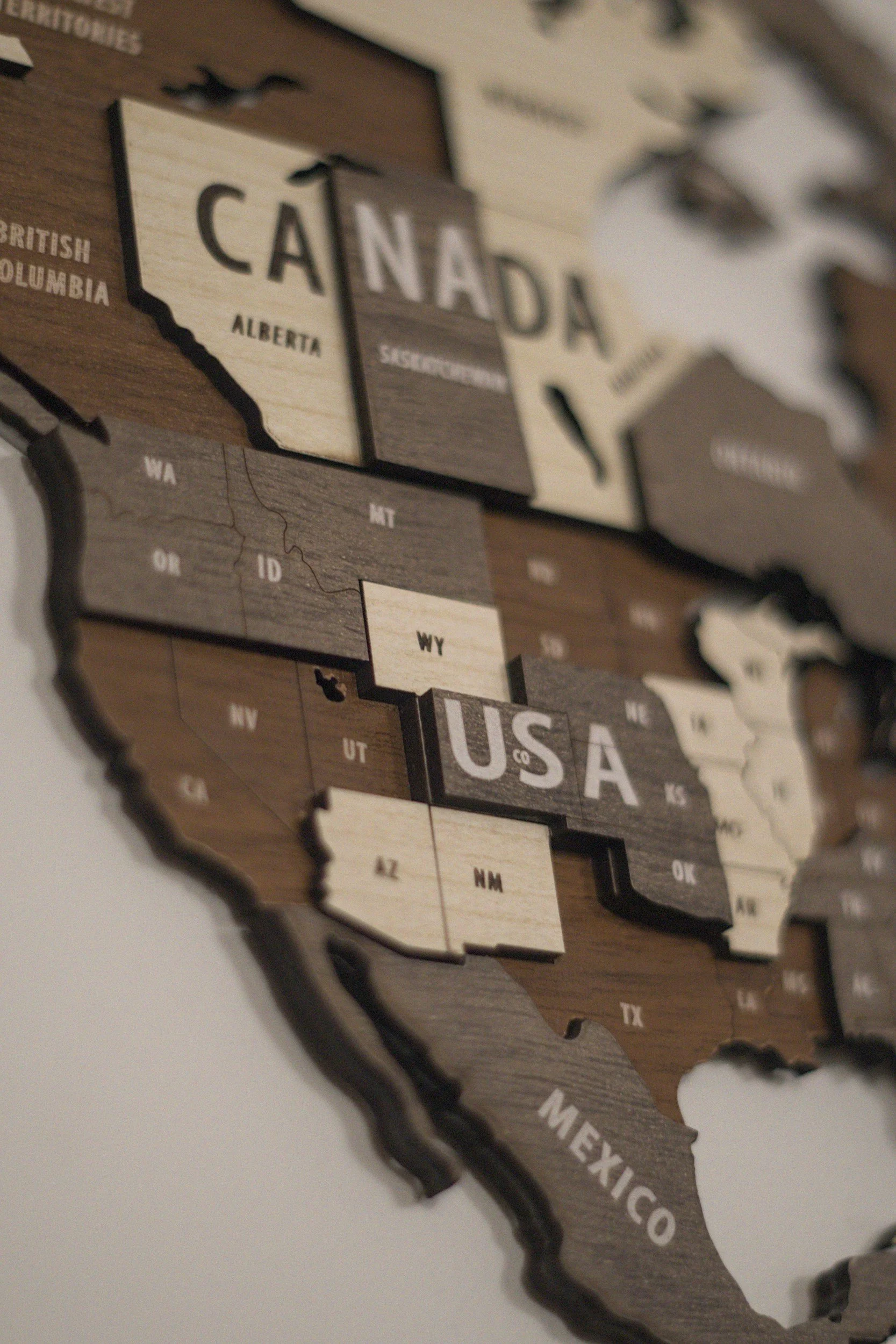 Close-up of a wooden map of North America with the United States, Canada, and Mexico labeled, showing the US in the center.
