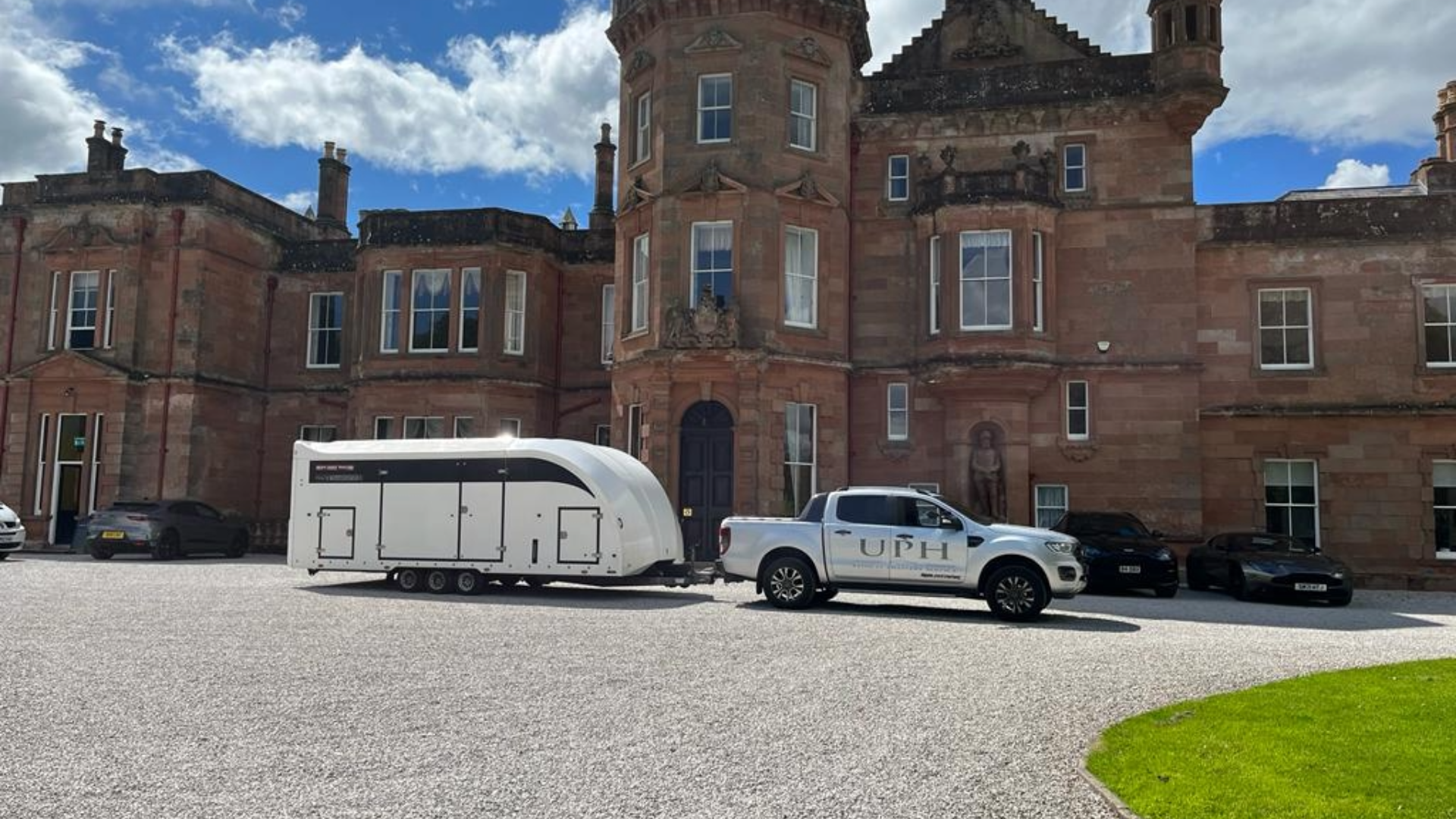 Enclosed trailer delivering luxury vehicle to estate