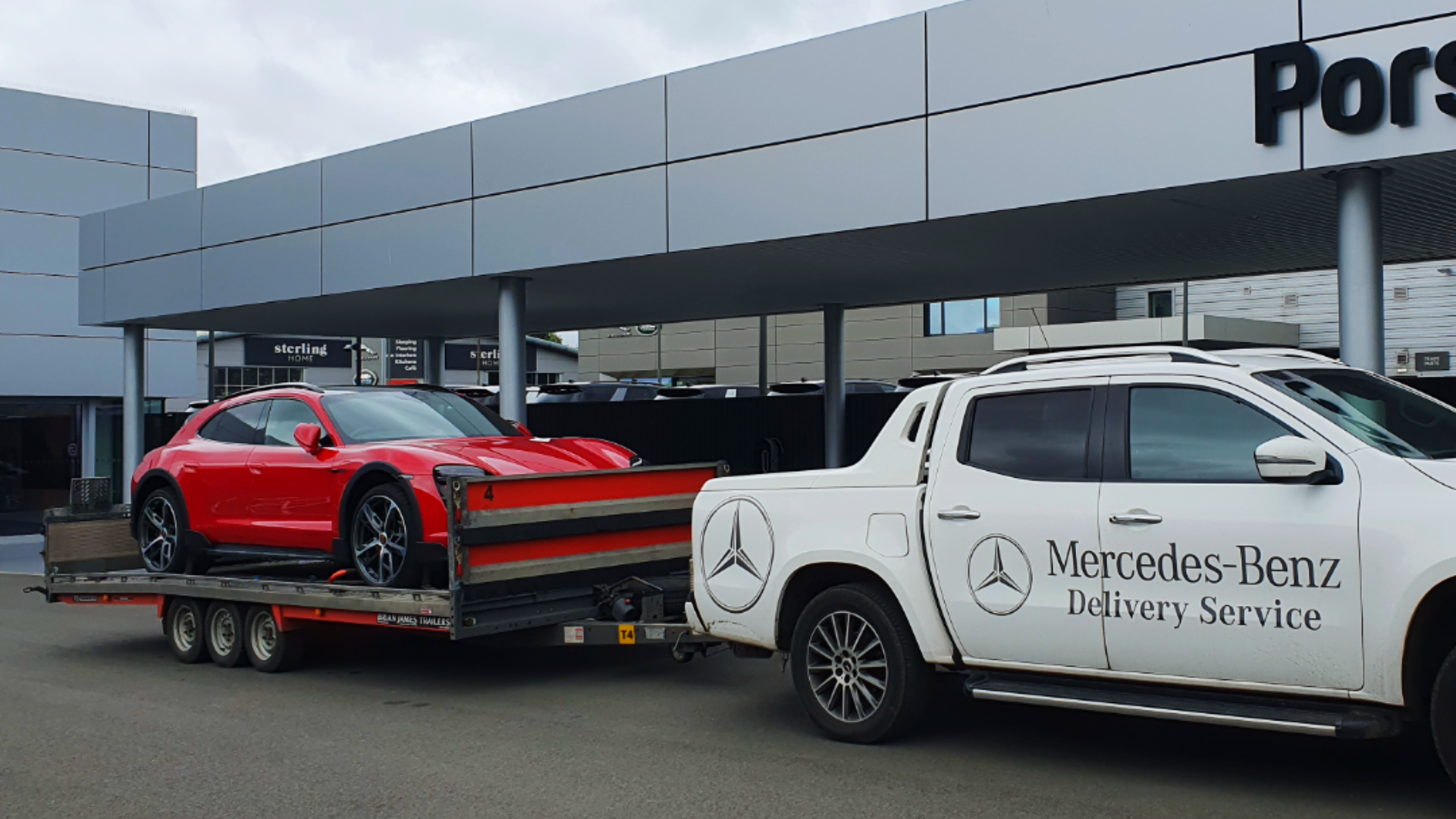 Porsche attached to single vehicle trailer outside dealership