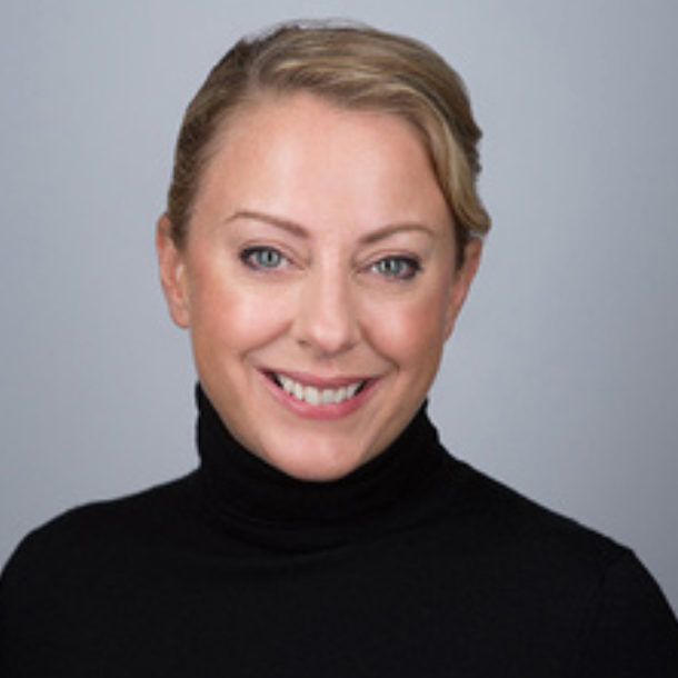 Smiling person in black turtleneck against gray background.