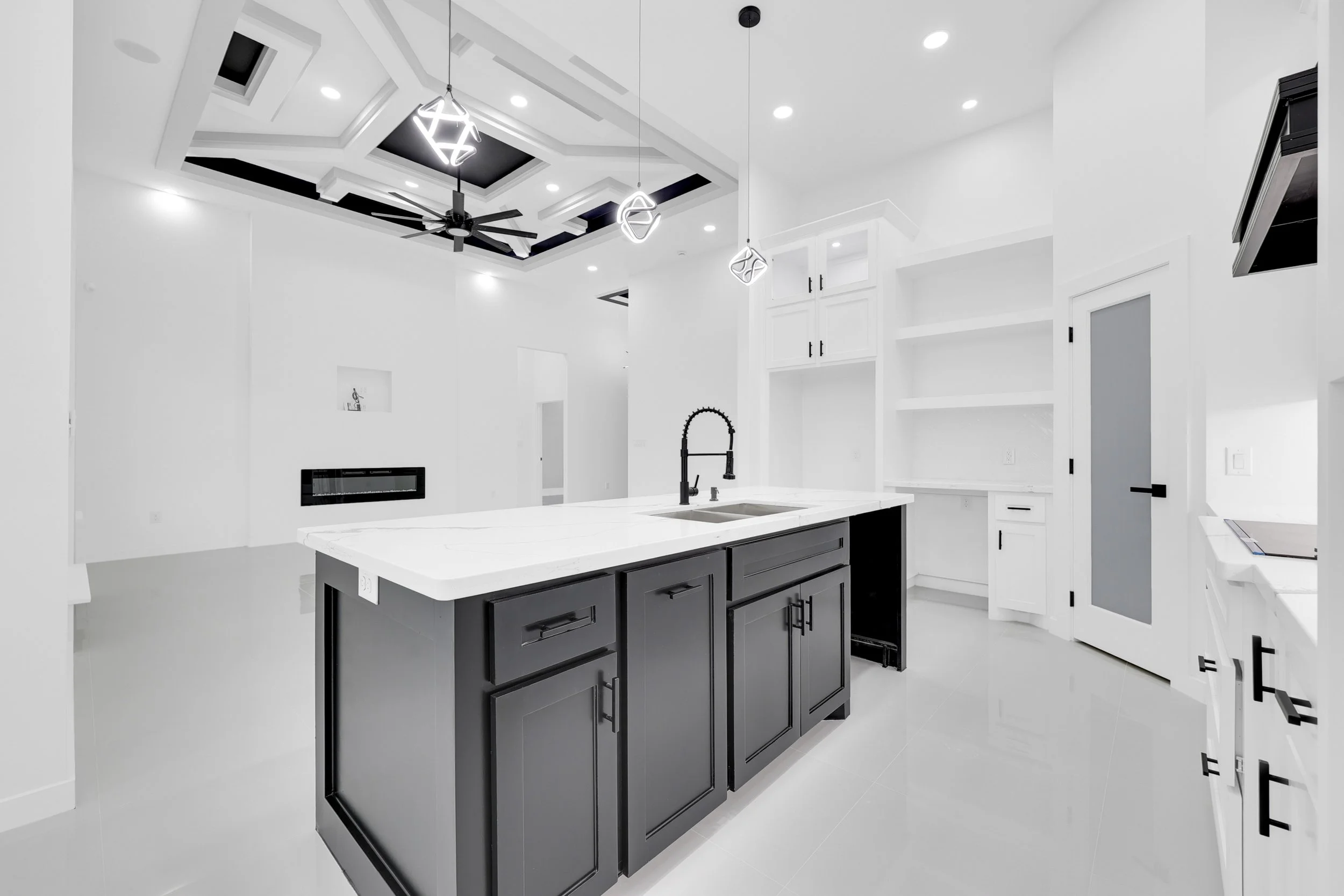 Modern white kitchen with black island and pendant lights