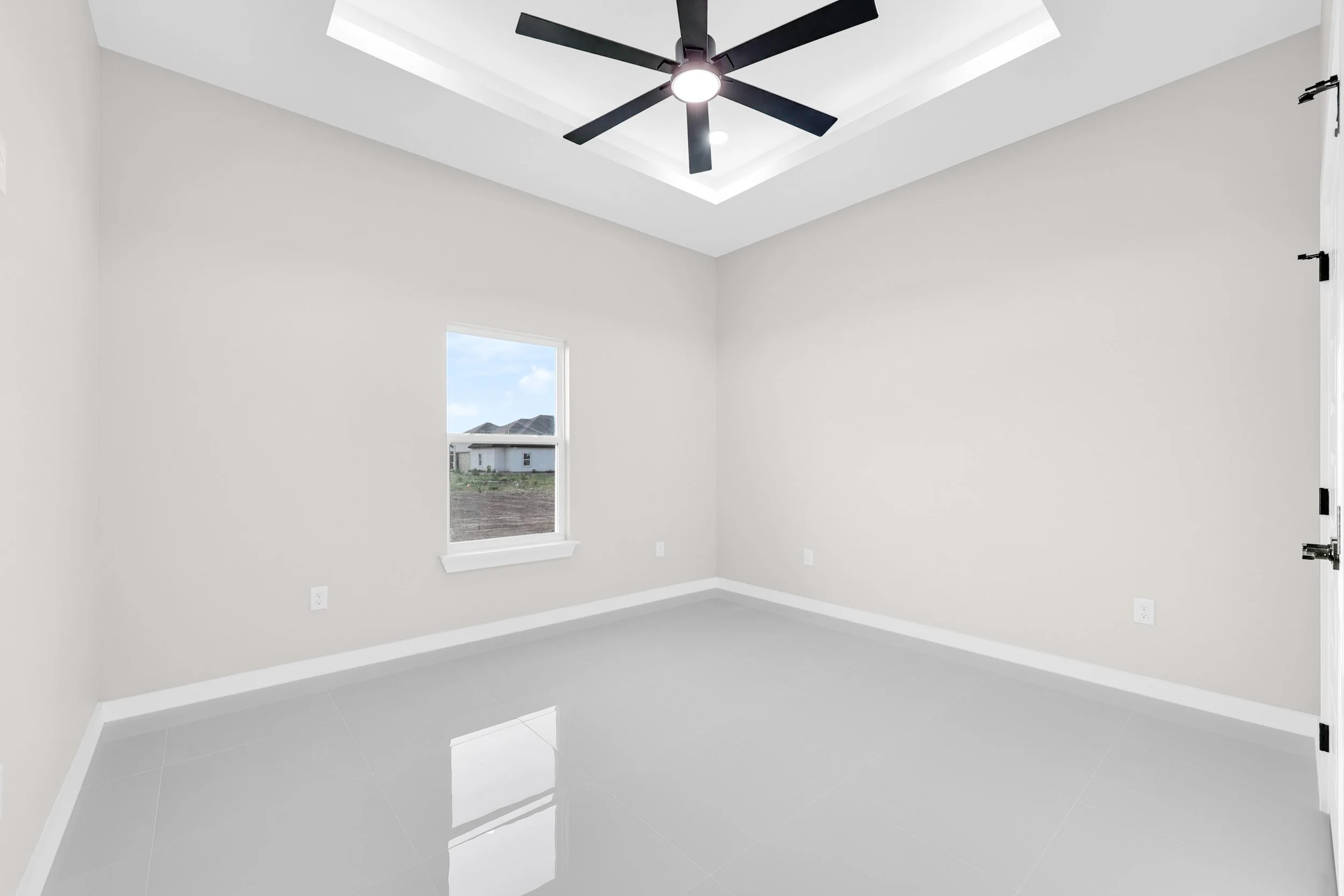 Empty room with white walls, glossy floor, window view, and ceiling fan.