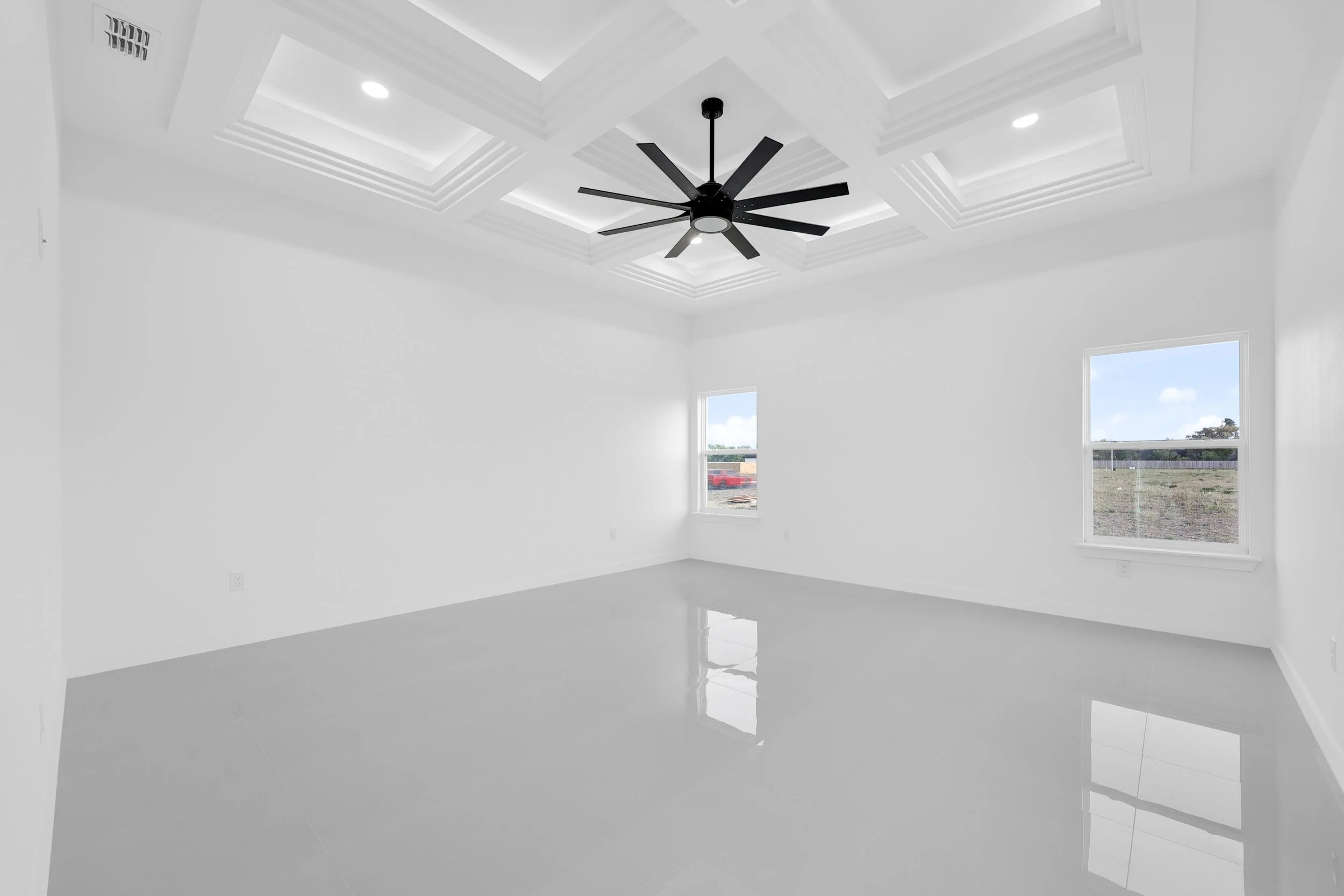Empty modern room with a coffered ceiling, black ceiling fan, glossy white floors, and two windows.