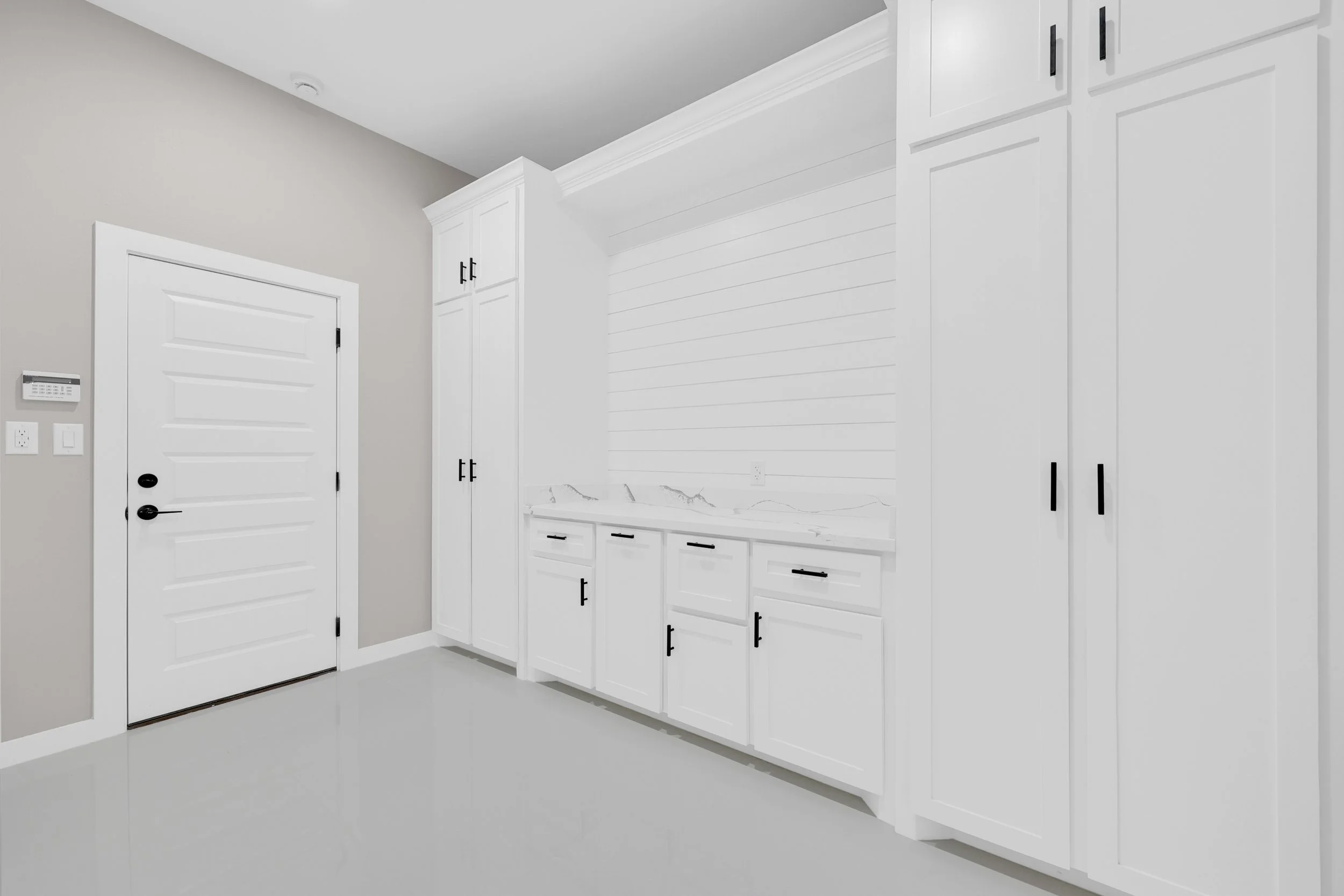 White laundry room with cabinets, countertop, and a door