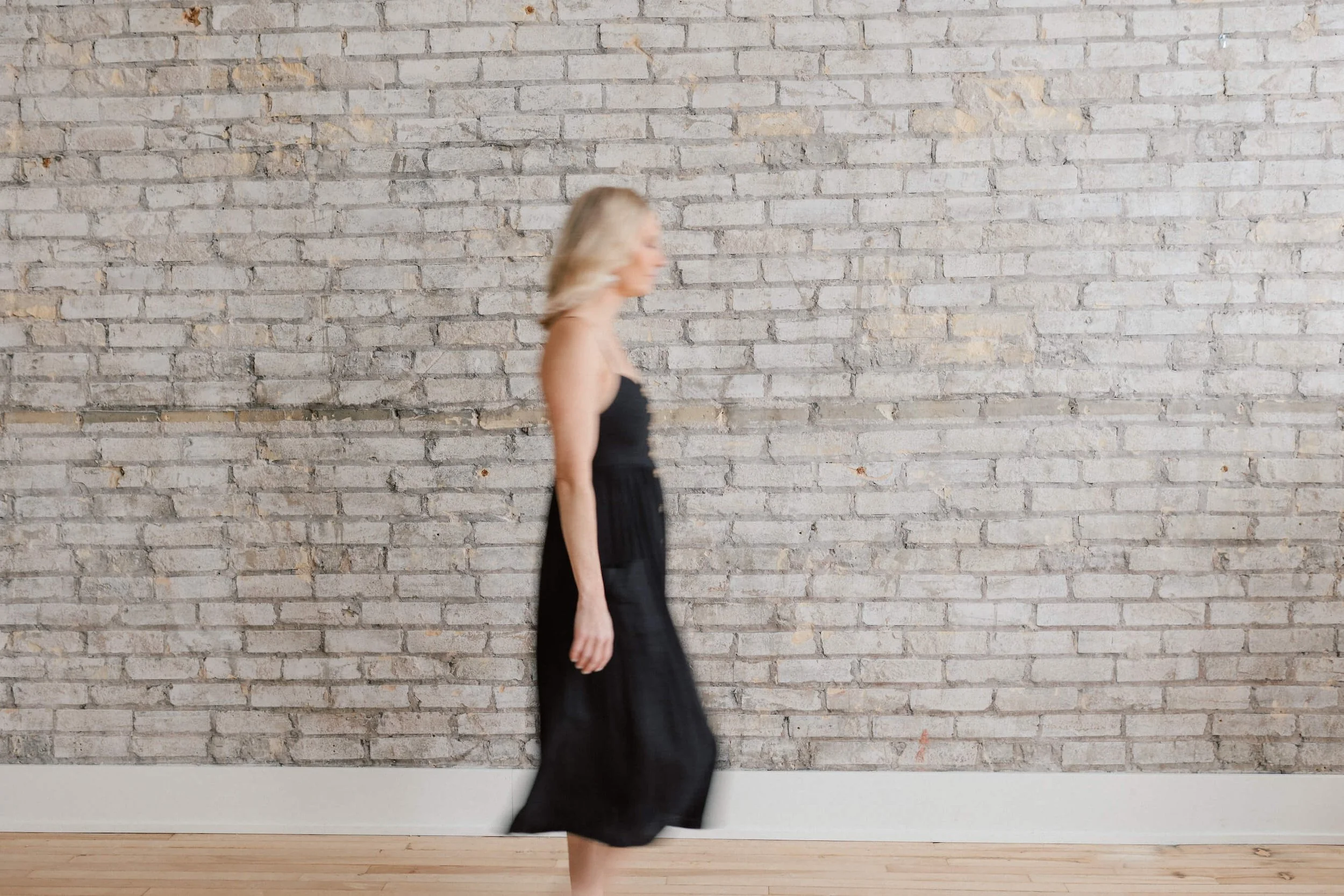 blurred side profile of lara ellis walking against brick background