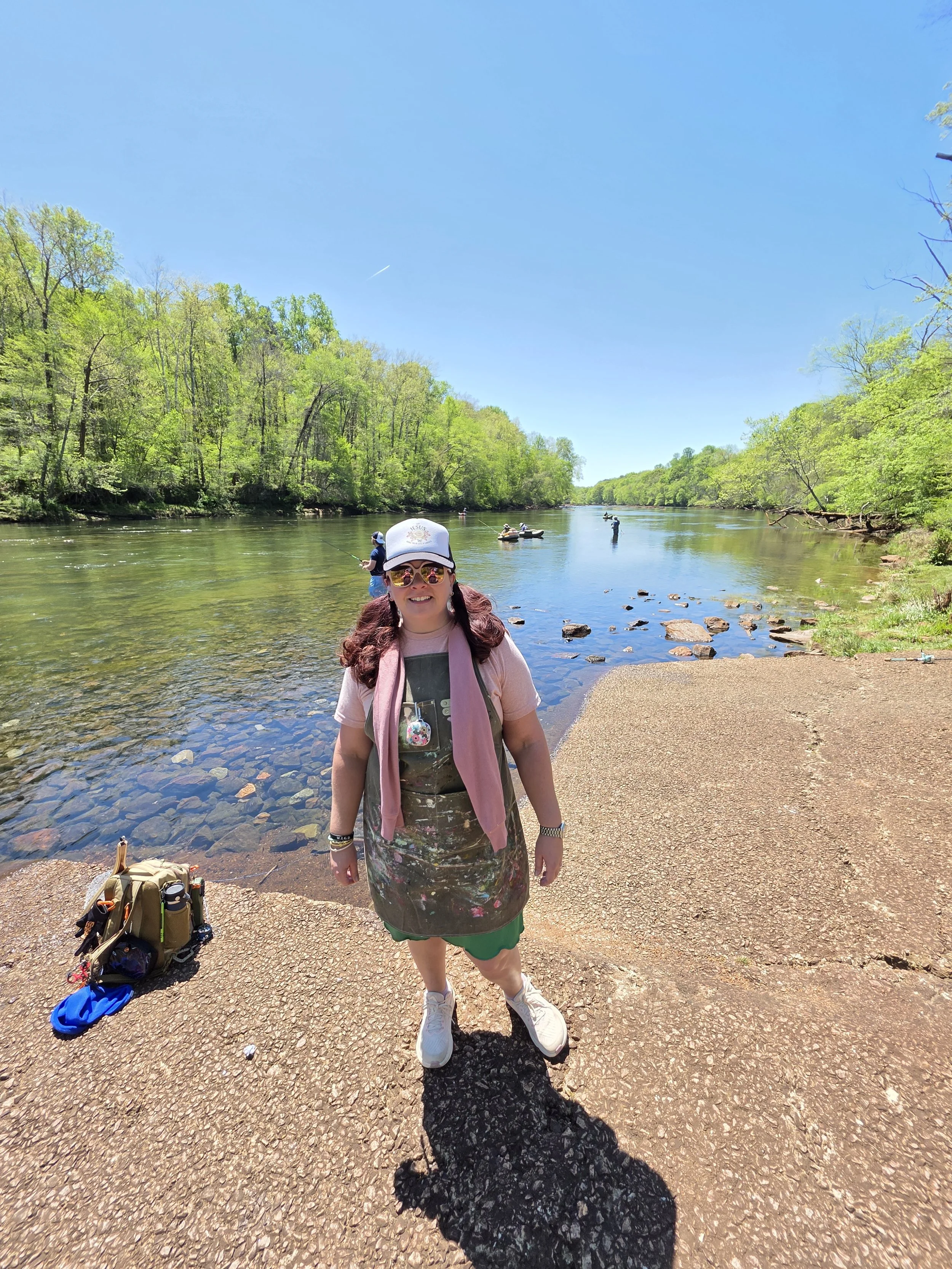 Jennifer Mehling painting outdoors beside a peaceful river, finding inspiration in God's creation.