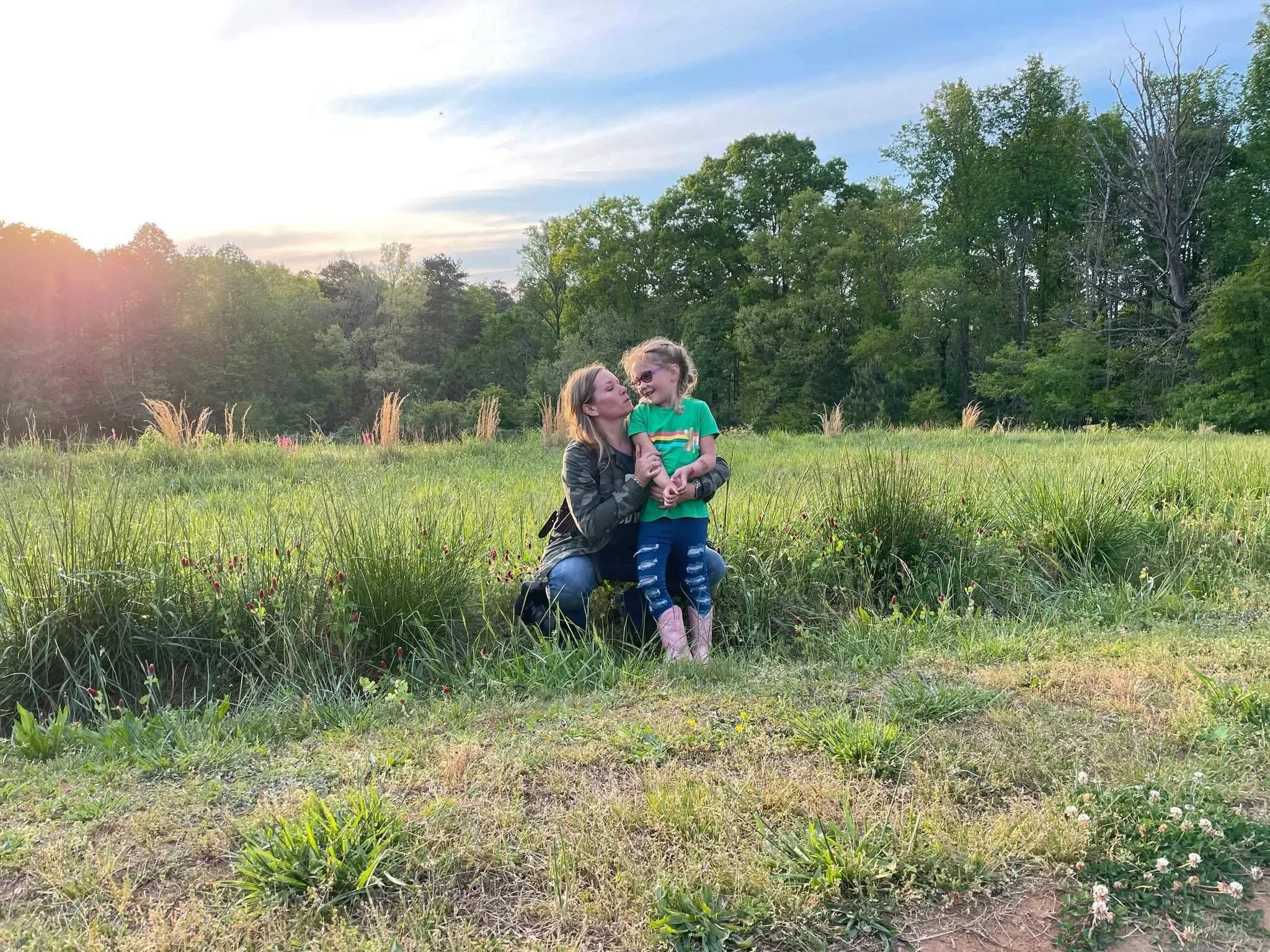 Jennifer Mehling sharing a peaceful moment with her daughter in a sunlit meadow, celebrating God's creation and family.