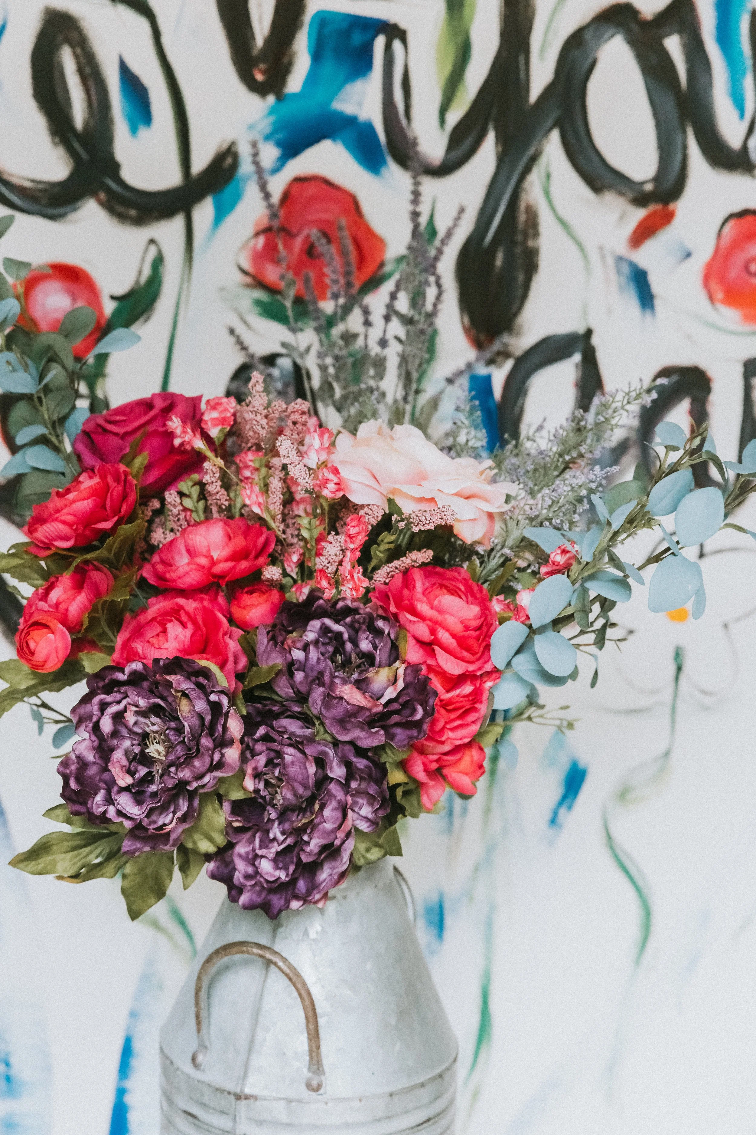 A close-up floral arrangement with pink, red, and purple flowers in a vase, symbolizing beauty, growth, and a life being tended with care.