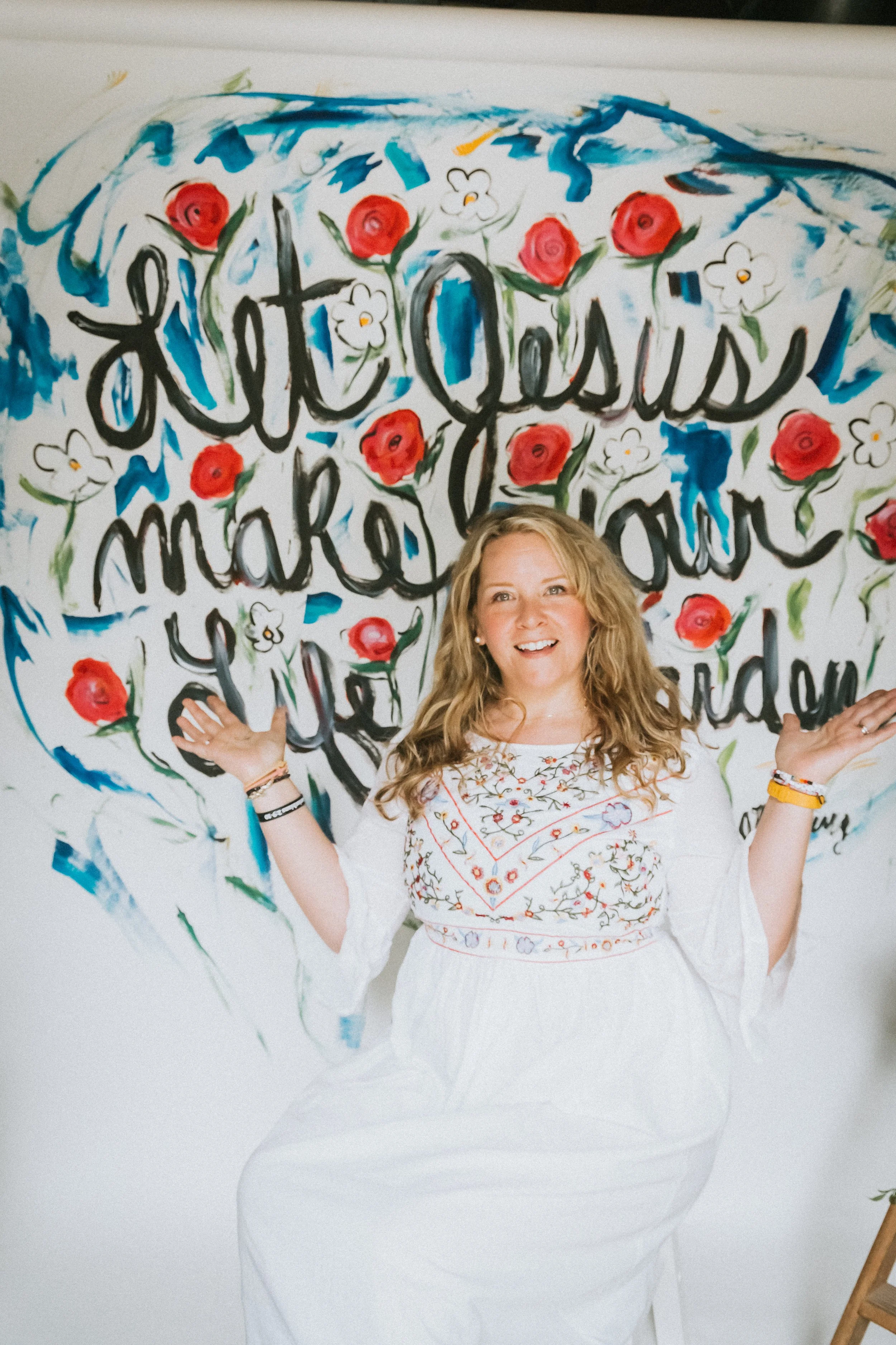 Jennifer Mehling standing peacefully in a white dress in front of a painted wall, representing calm, spiritual growth, and being rooted in Christ.