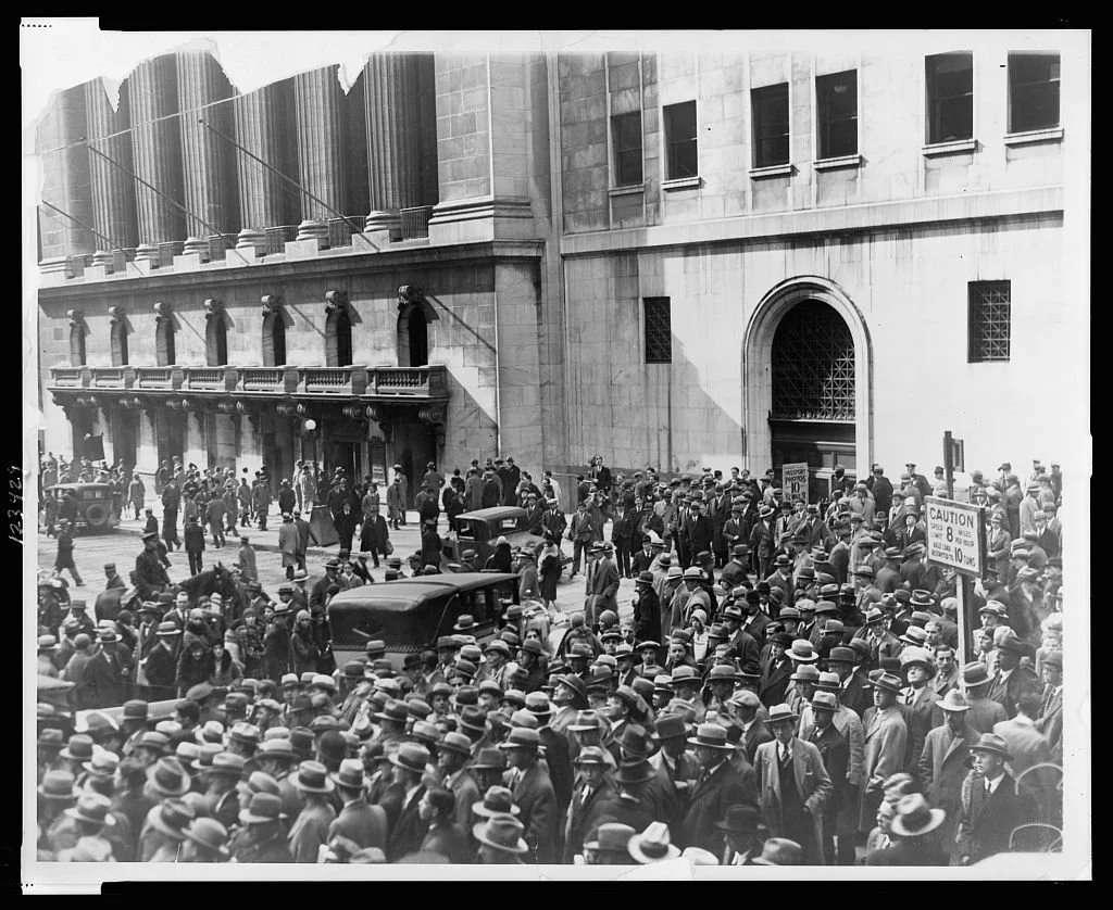 Black-and-white photograph of a large crowd gathered on a New York street outside the Stock Exchange after the stock market crash of 1929