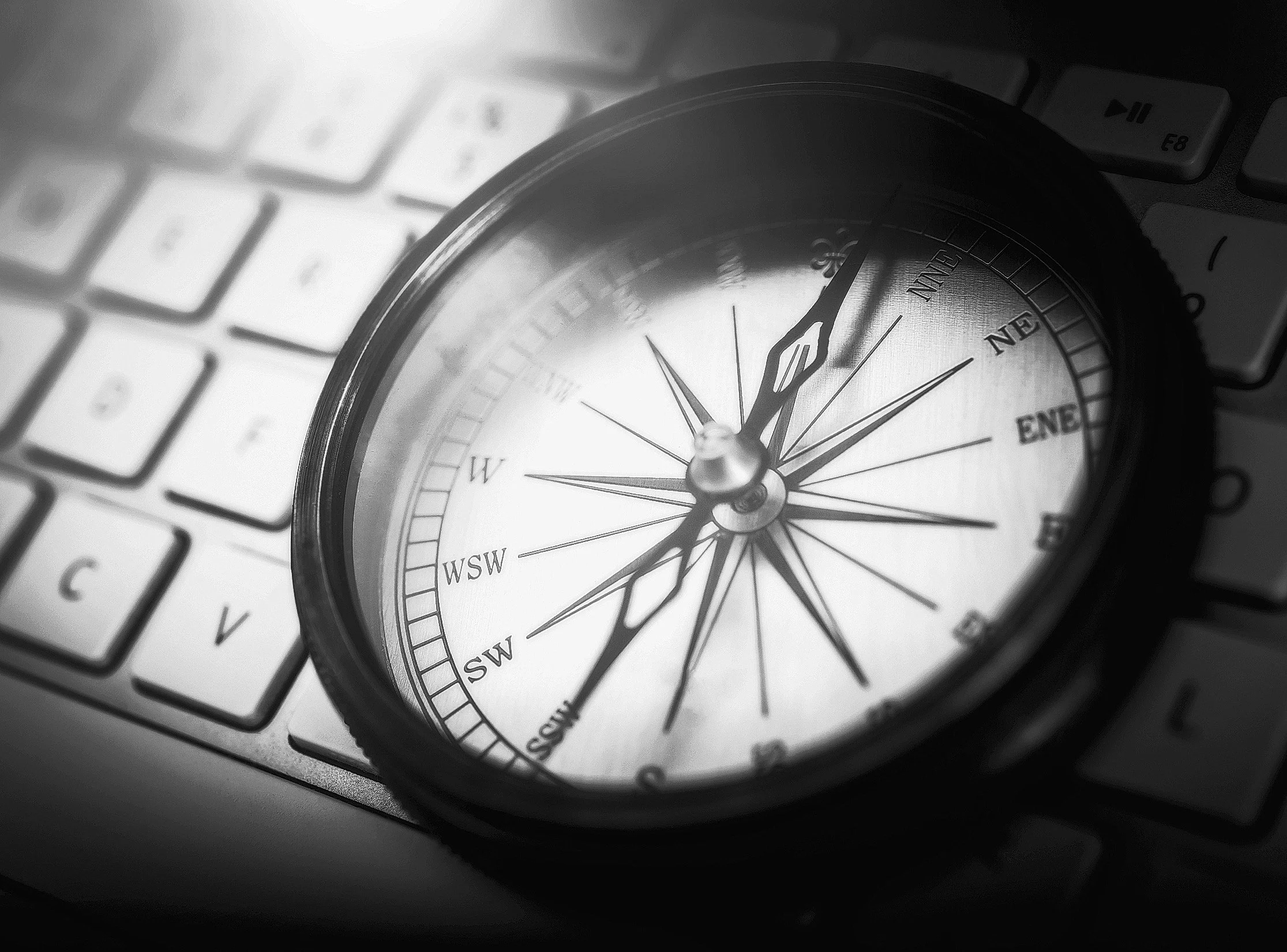 Close-up of a compass on a computer keyboard with dramatic lighting