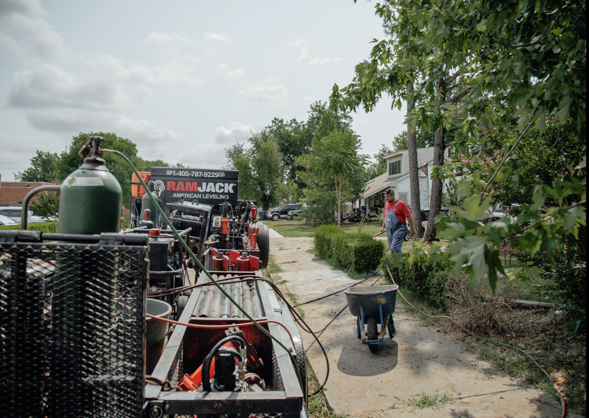 Ram Jack foundation repair crew and specialized equipment on-site preparing for a residential foundation stabilization project