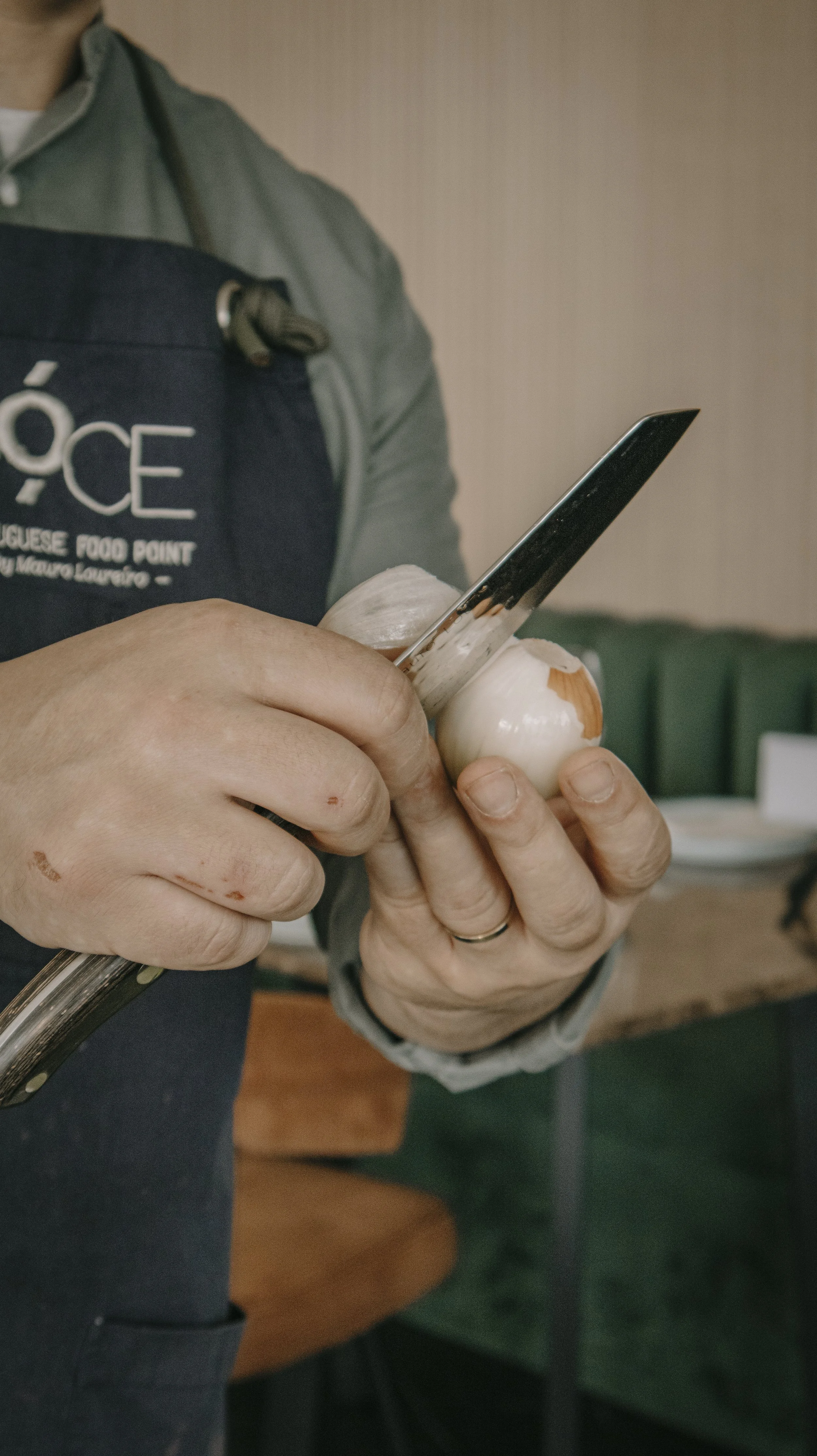 Pessoa descascando uma cebola com uma faca em uma cozinha.