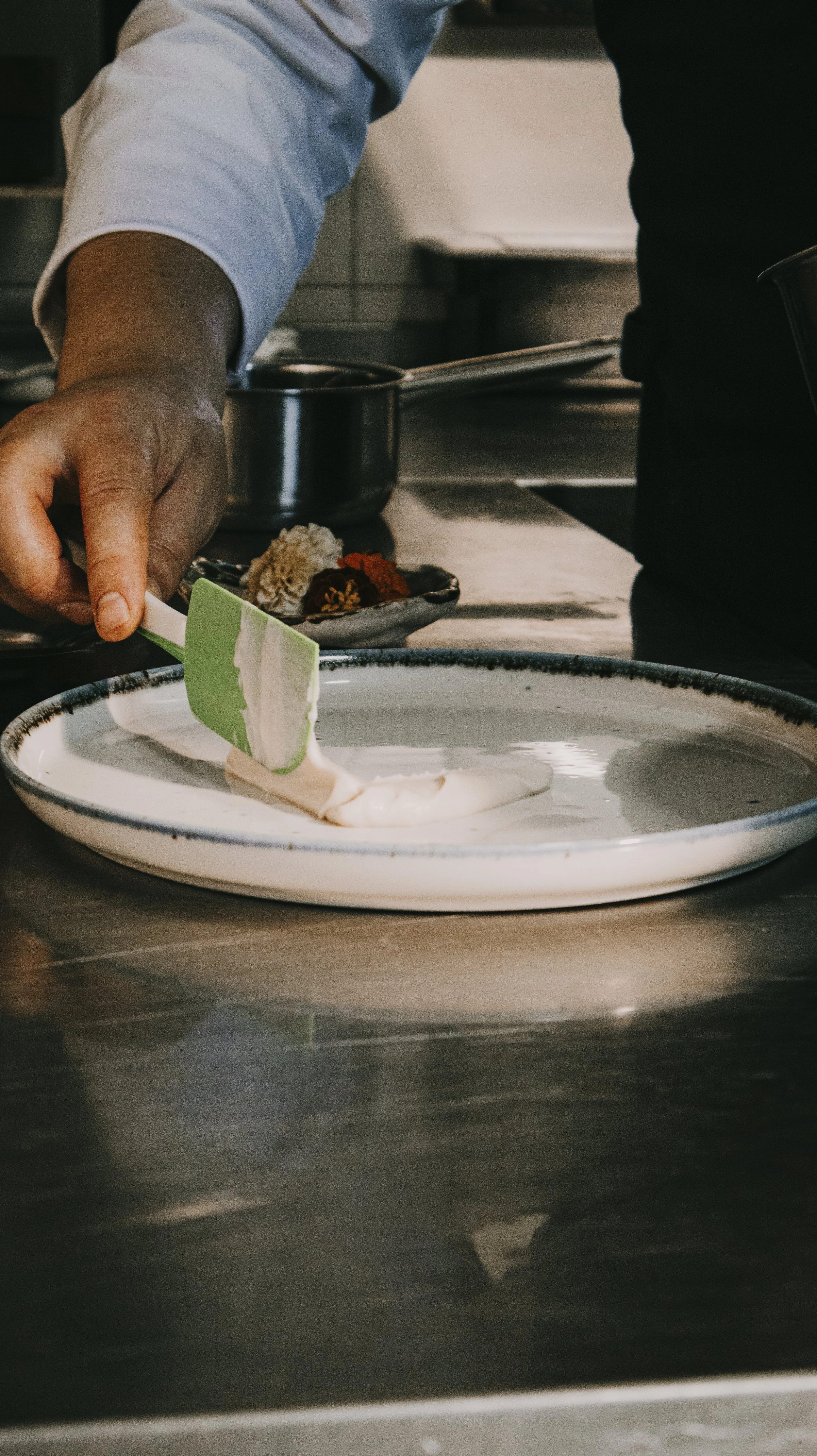 Chef colocando creme ou sorvete em um prato raso na cozinha.