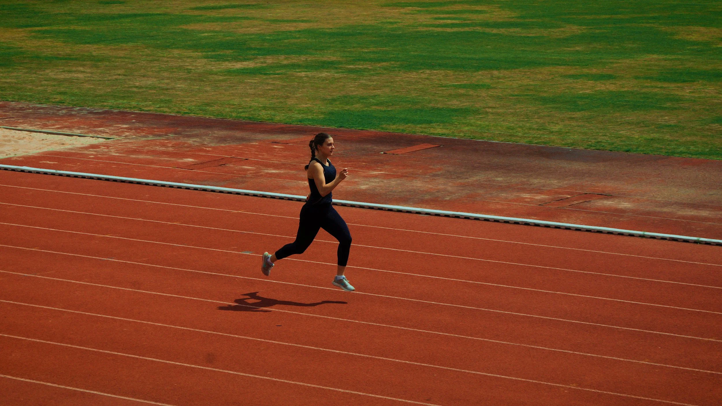 Pessoa correndo na pista de atletismo ao ar livre