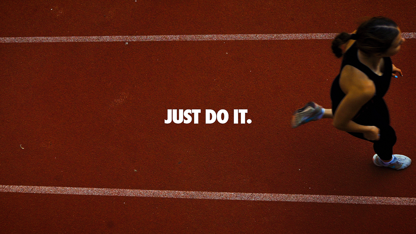 Pessoa correndo na pista de atletismo com o texto 'Just do it' no centro da imagem.