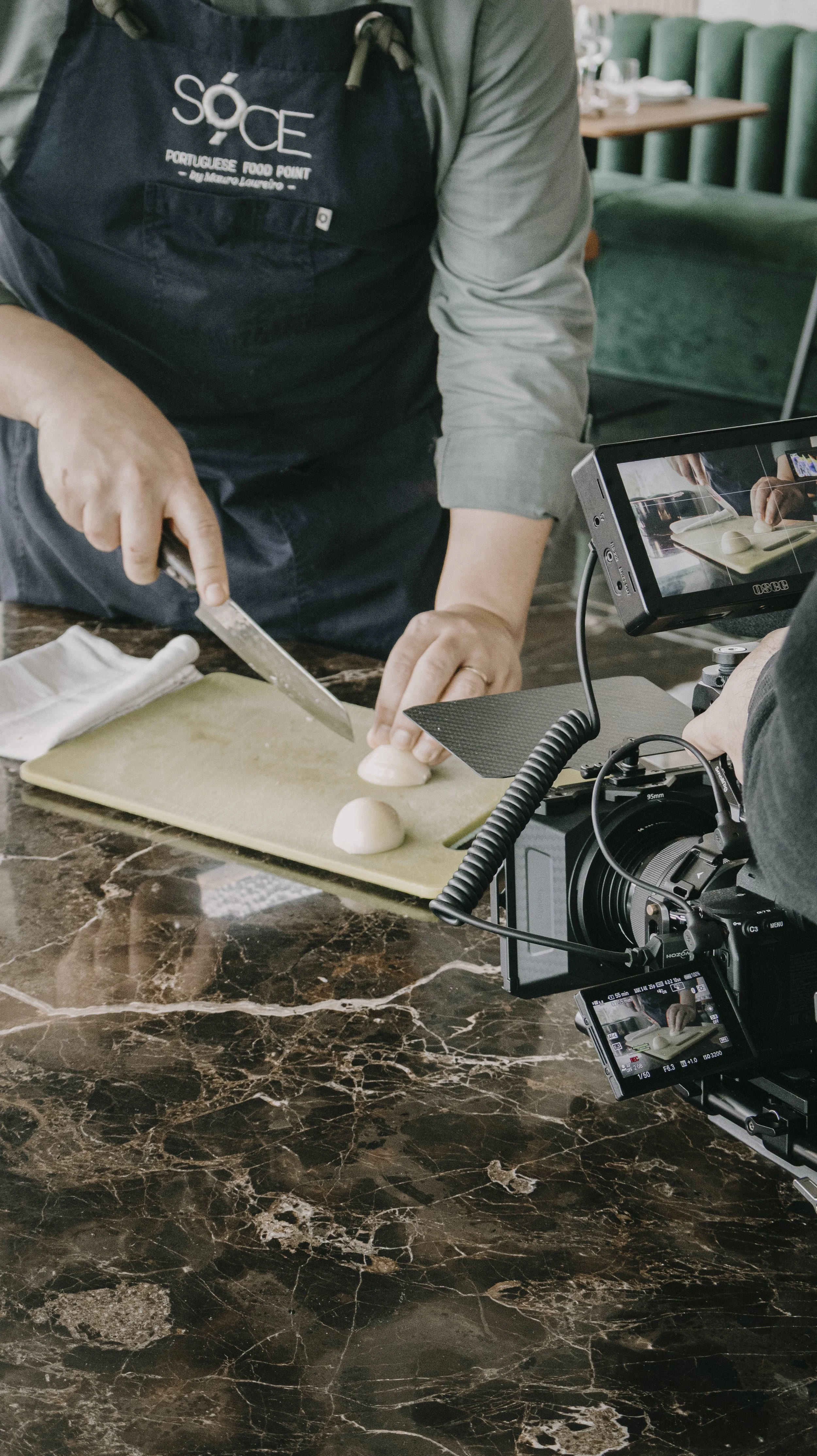 Pessoa preparando ovos em uma cozinha, com câmera filmando, em ambiente de gravação culinária.