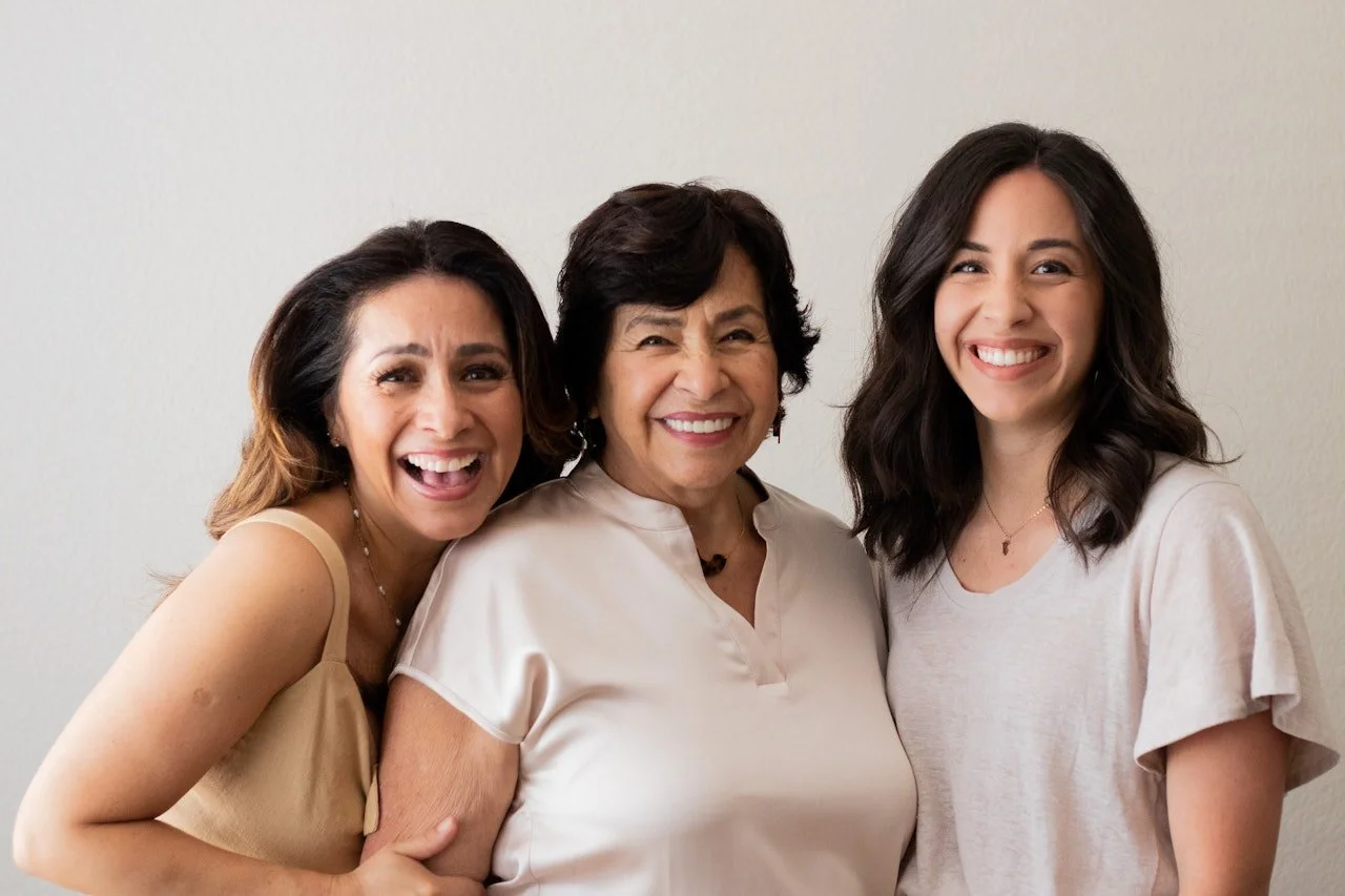 A mother and her two adult daughters smiling together