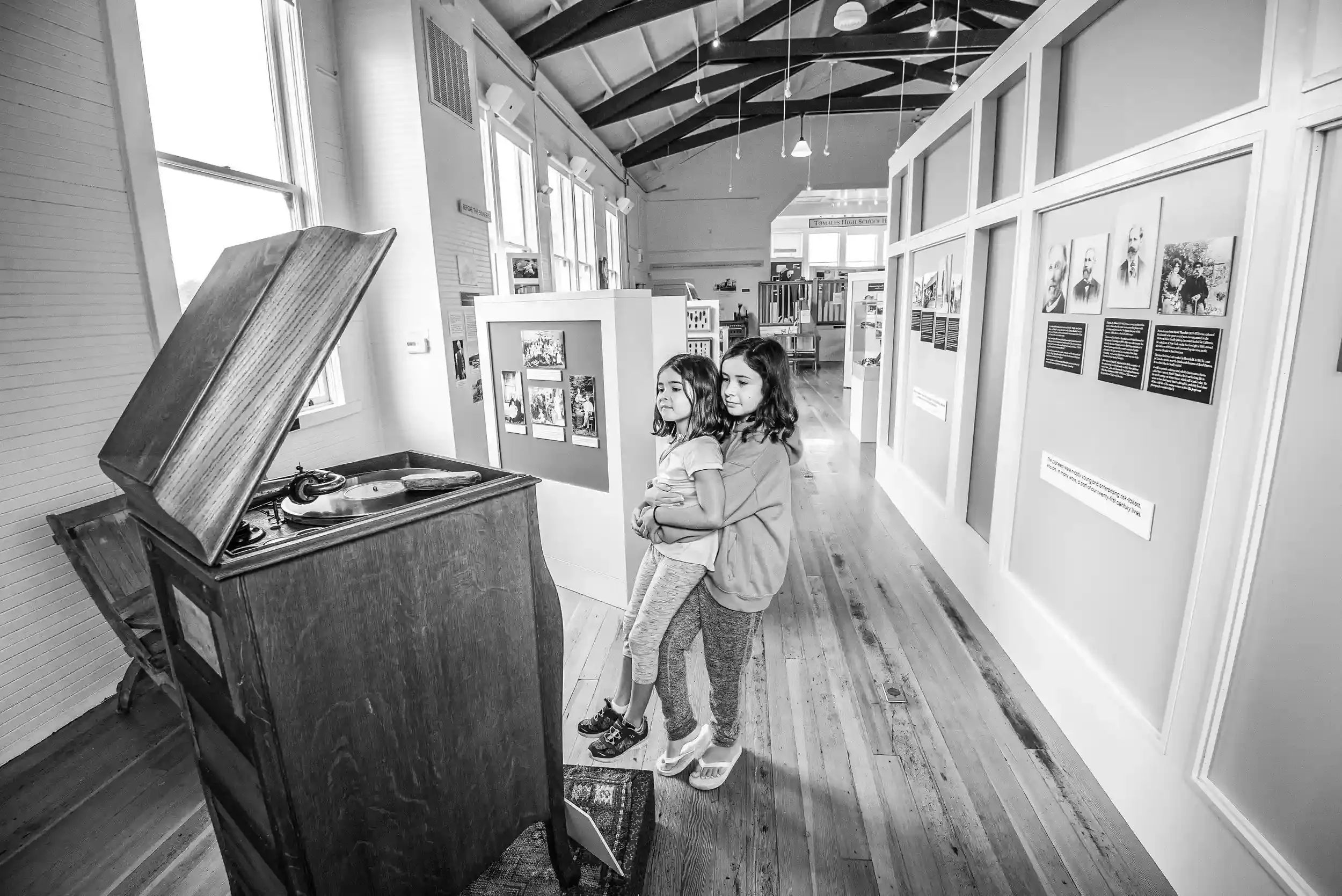 Two young girls looking at a vintage record player in an art gallery.